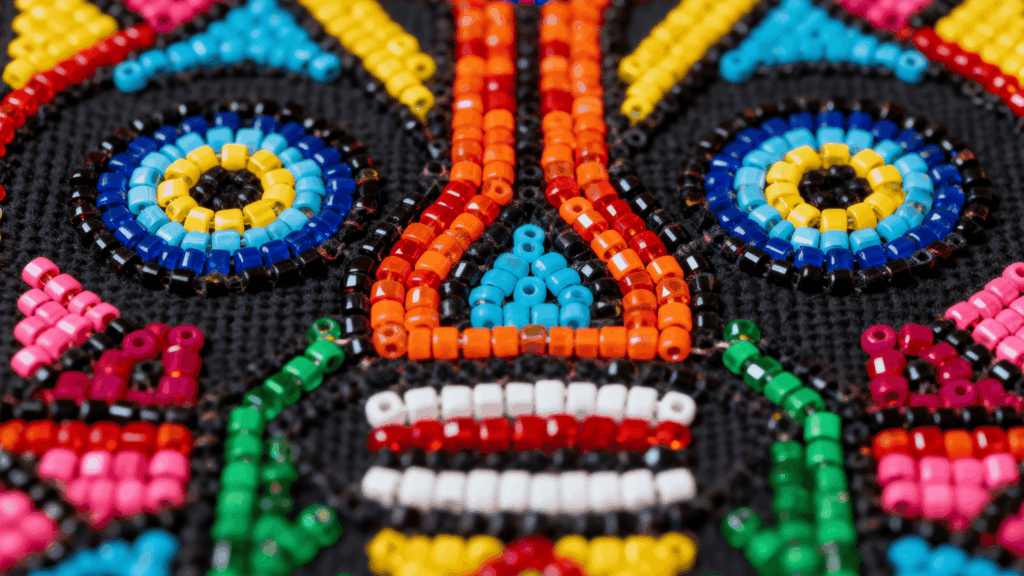 Close-up of Huichol beadwork with vibrant geometric patterns, colorful glass beads forming traditional symbolic design on dark base
