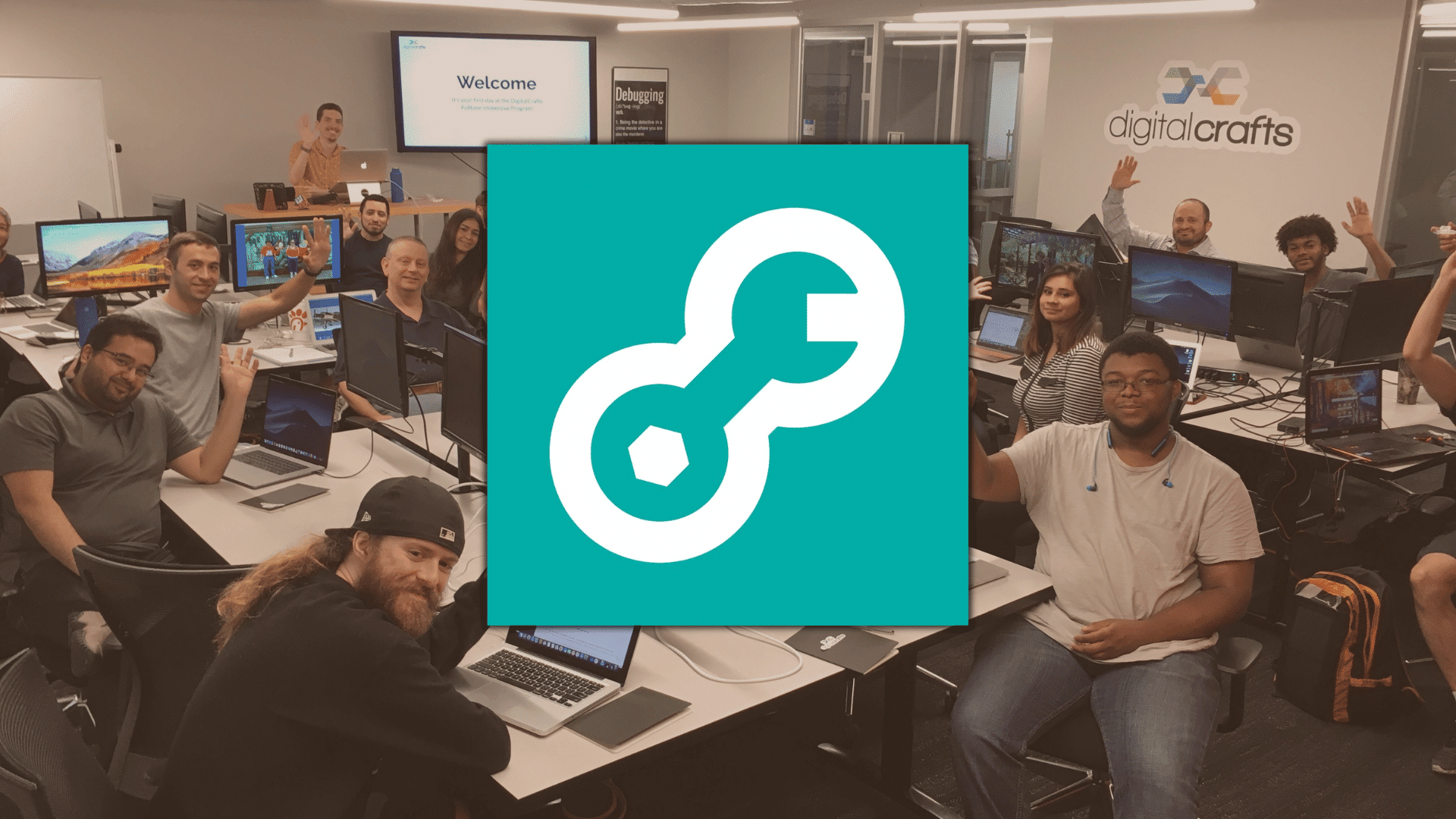 DigitalCrafts classroom with students at computers, smiling and raising hands during a coding session in a modern training space