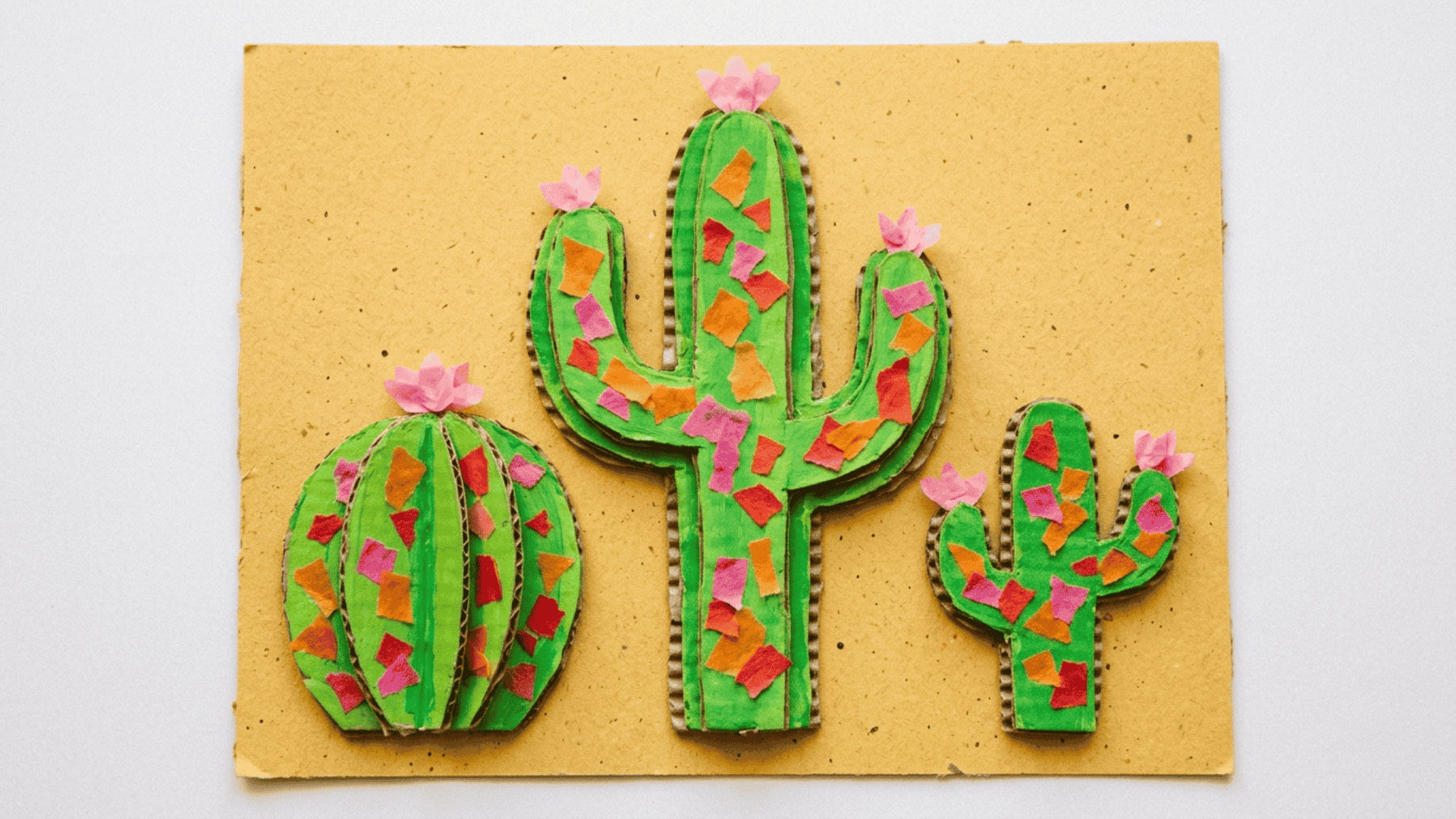 cardboard cactus collage showing layered green cardboard cactus shapes with tissue paper texture and pink paper flowers on tips