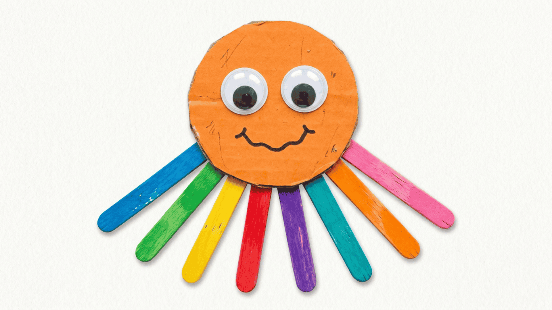 craft stick octopus craft showing eight colorful painted sticks as legs beneath an orange cardboard head with googly eyes