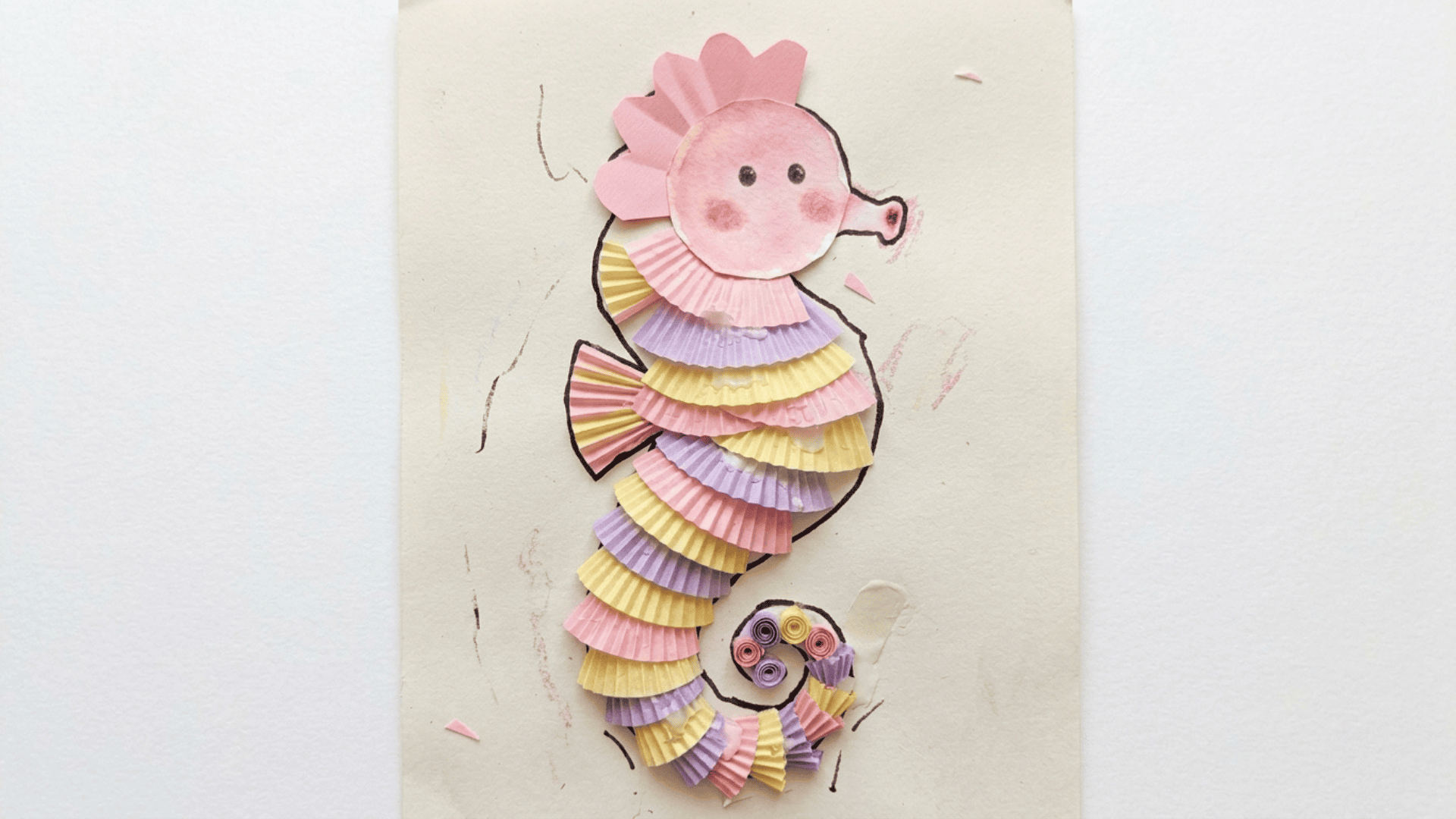 cupcake liner seahorse craft showing alternating pink yellow and purple liners stacked as body segments with a painted head and curled tail
