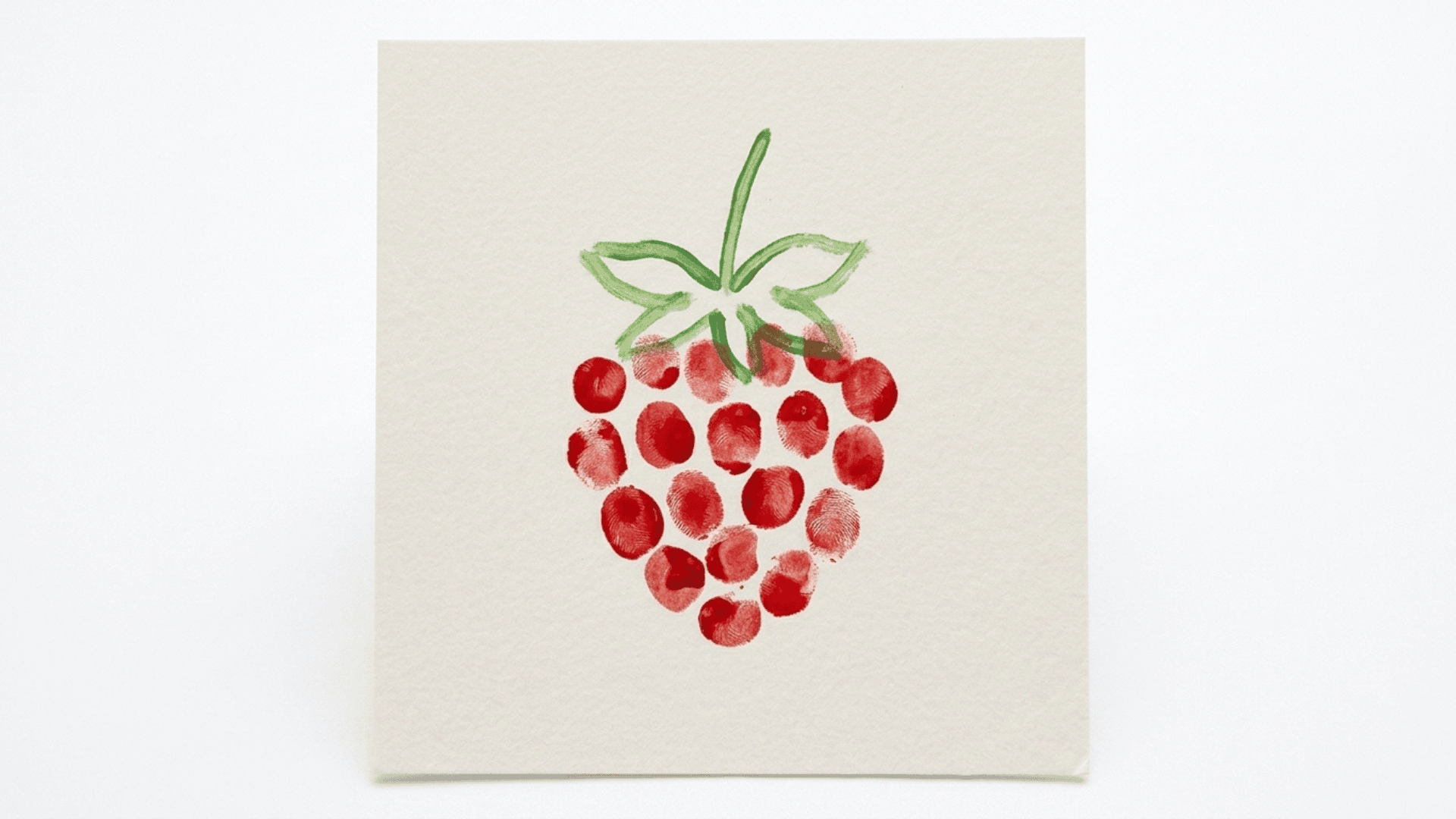 fingerprint strawberry art showing red fingerprint dots forming a strawberry shape with green painted leaf lines on paper