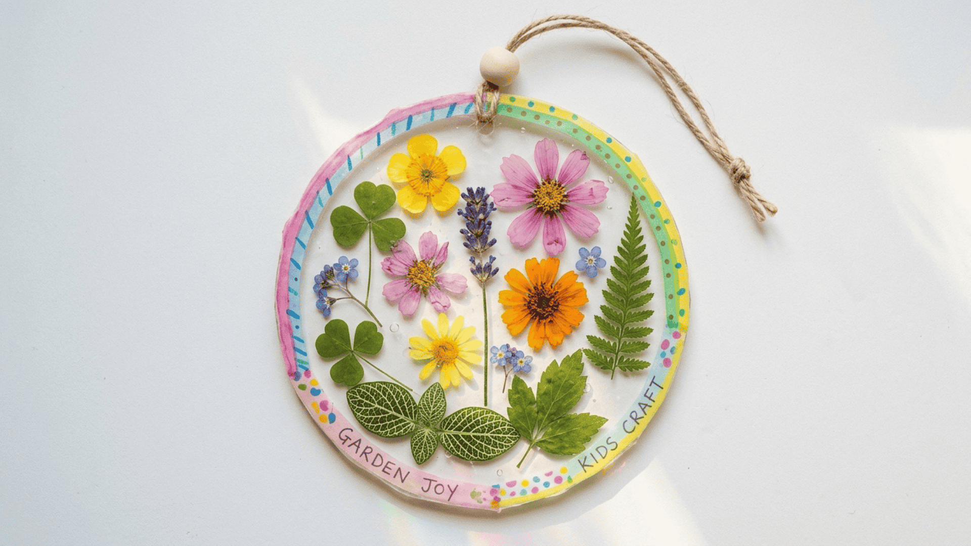flower sun catcher with pressed leaves and petals on white background showing colorful transparent design