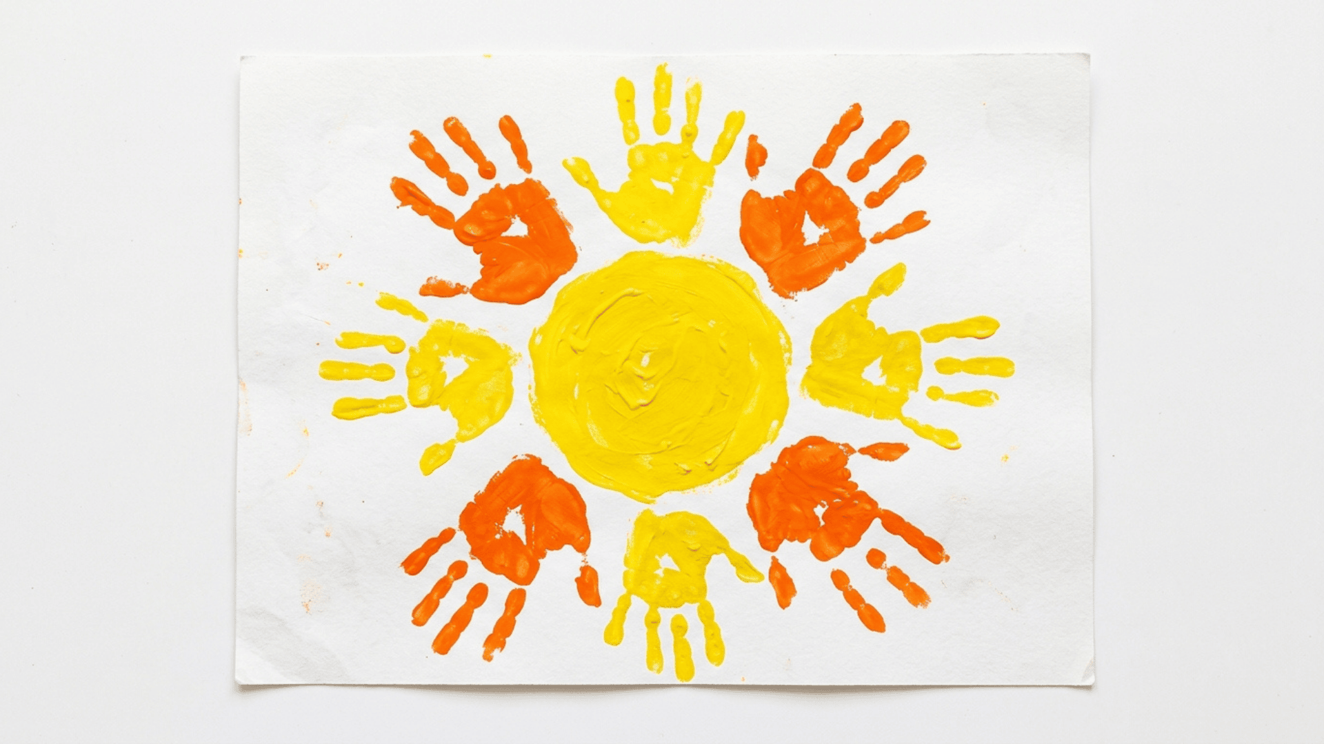 handprint sun art painting with orange and yellow painted handprints forming sun rays on white paper for kids