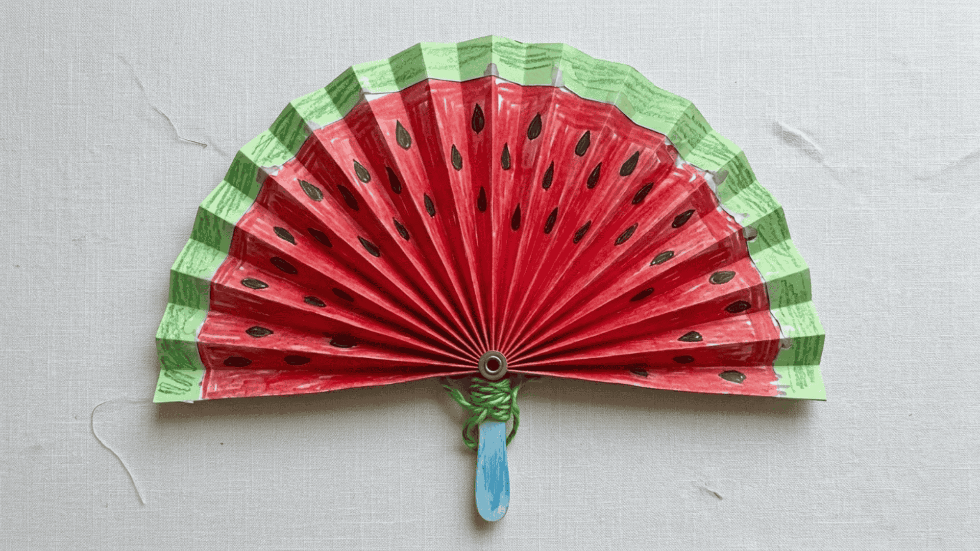 paper fan watermelon craft showing accordion folded paper decorated with green red and black watermelon colors for kids