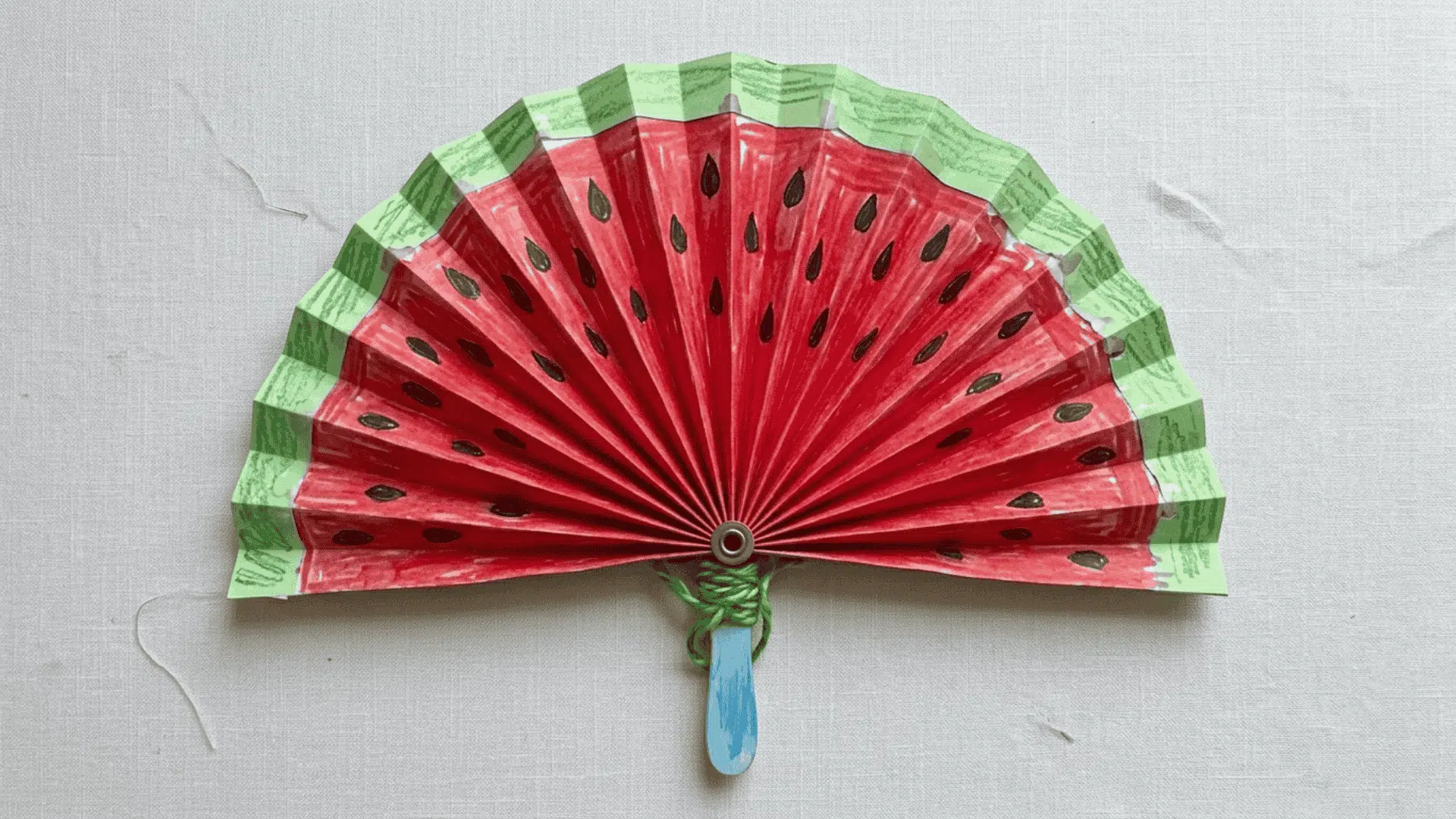 paper fan watermelon craft showing accordion folded paper decorated with green red and black watermelon colors for kids