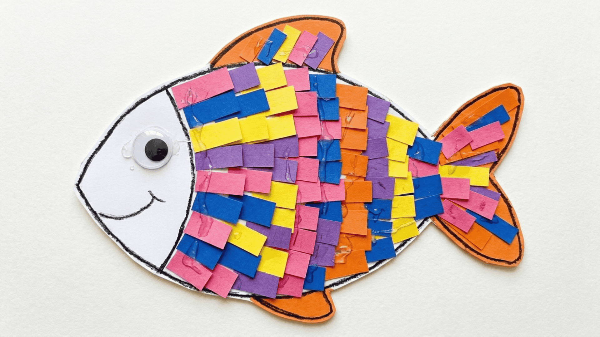 paper strip rainbow fish craft showing a fish outline filled with overlapping colorful paper strips in a scale pattern on white