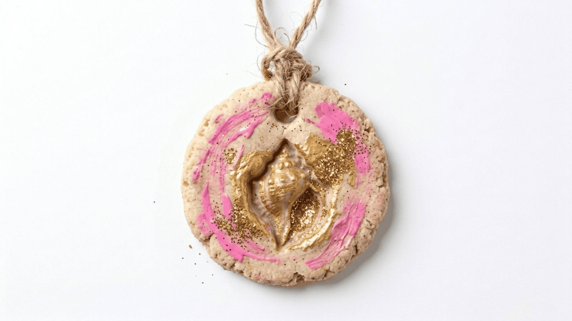 salt dough shell pendant showing a dried dough piece with a shell imprint painted in soft pink and gold with a string loop