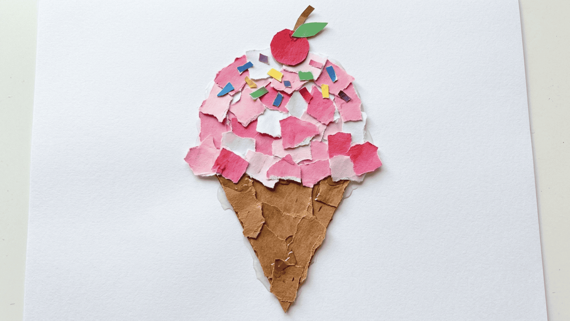torn paper ice cream cone craft showing a brown paper cone with pink and white torn paper pieces forming a soft scoop above