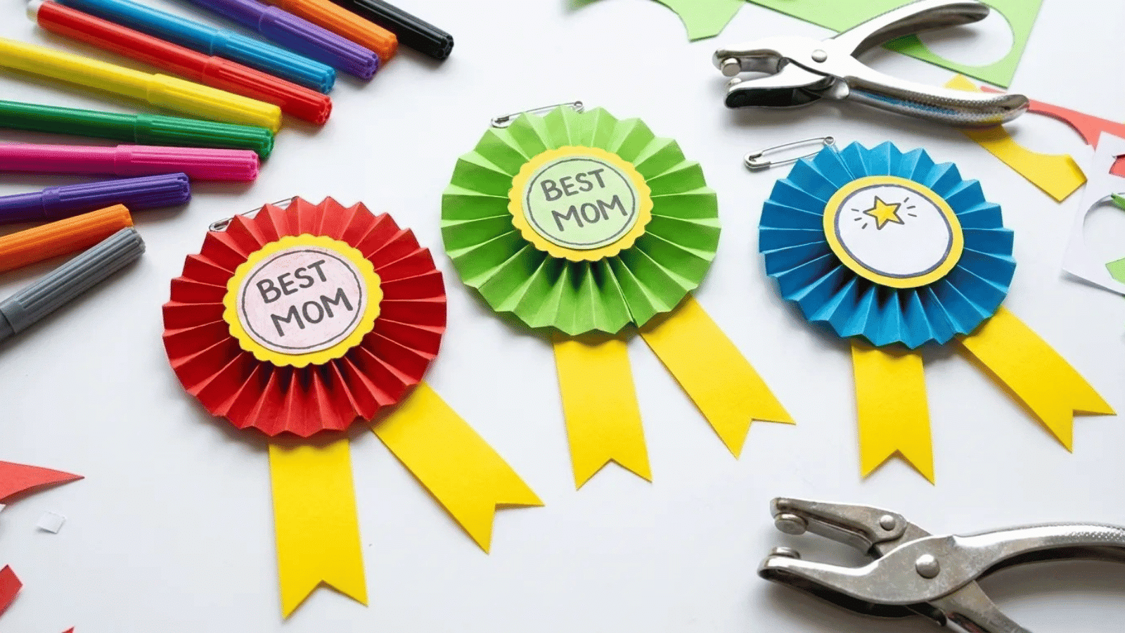 diy paper award rosettes labeled “Best Mom” and “Champion” with craft supplies, fun and creative appreciation gift idea