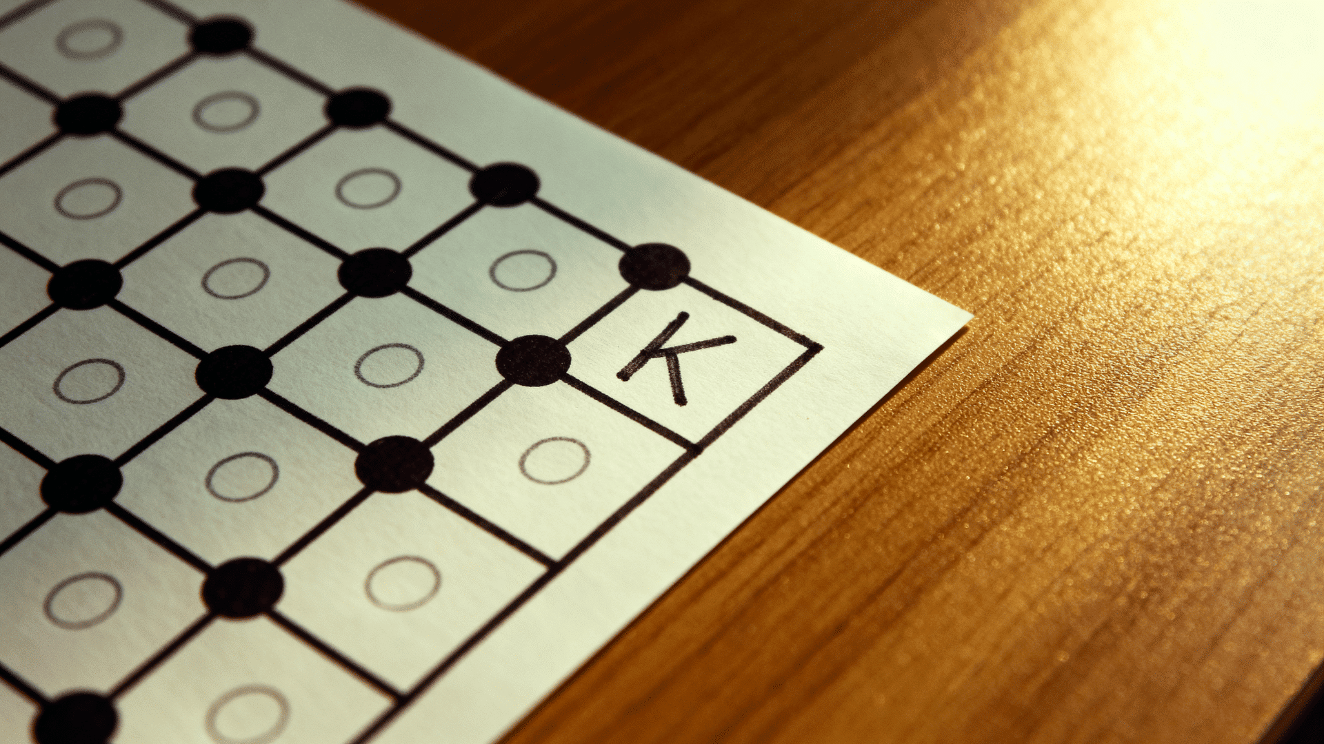 Dots and Boxes paper game with connected dots and a completed box marked with the letter K.