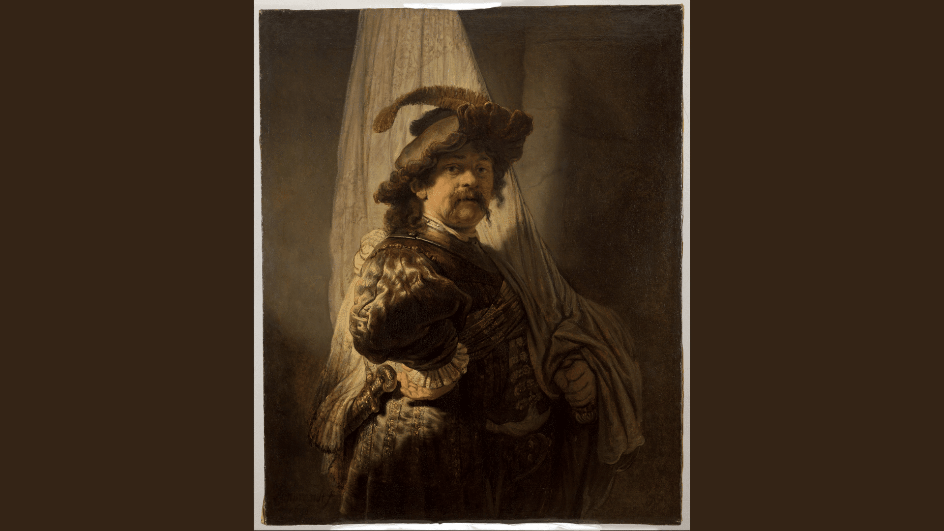 rembrandt’s dramatic portrait of a standard bearer holding a flag in rich historic clothing.
