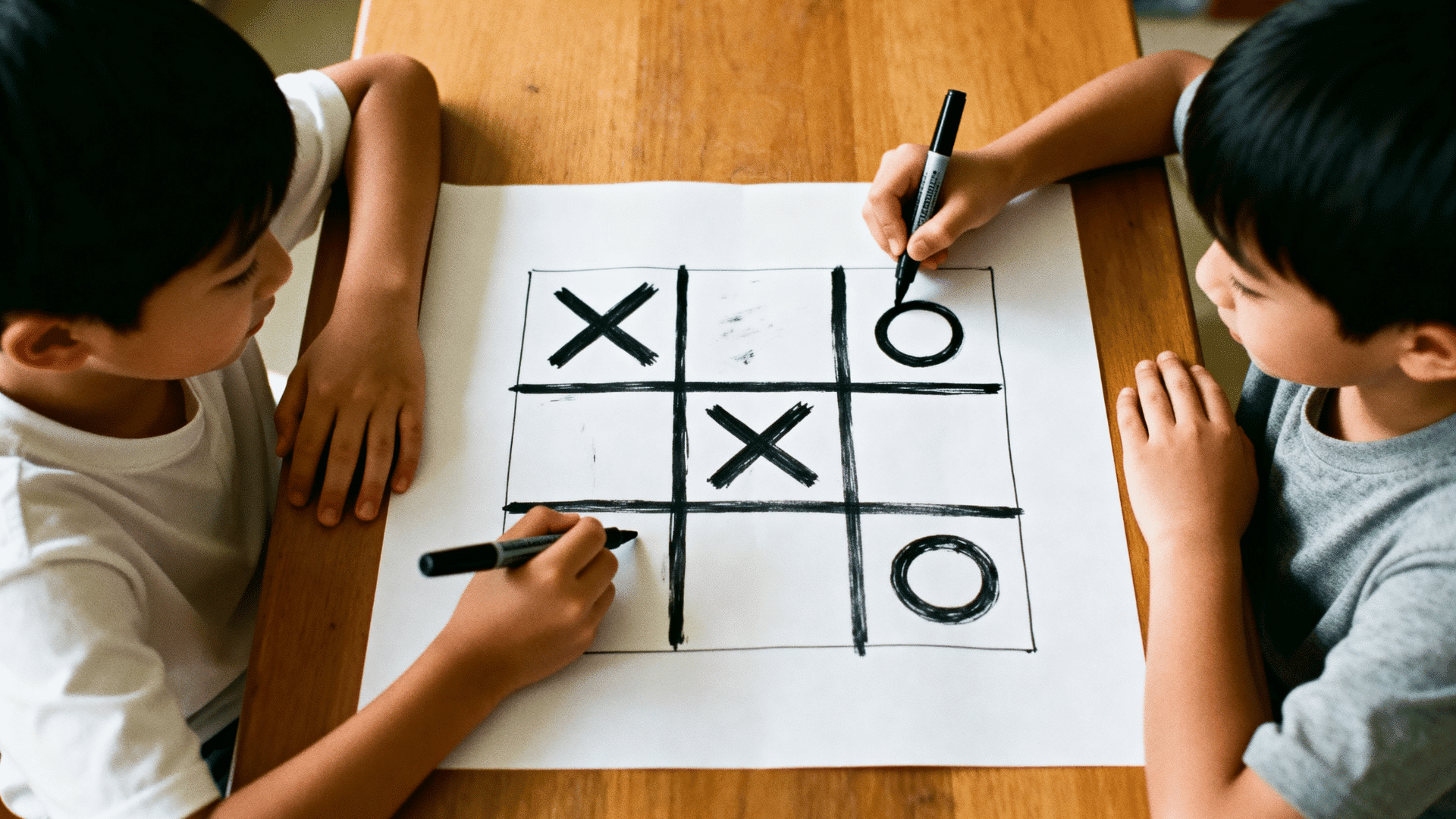 two kids play tic-tac-toe on paper with X and O marks using black markers.