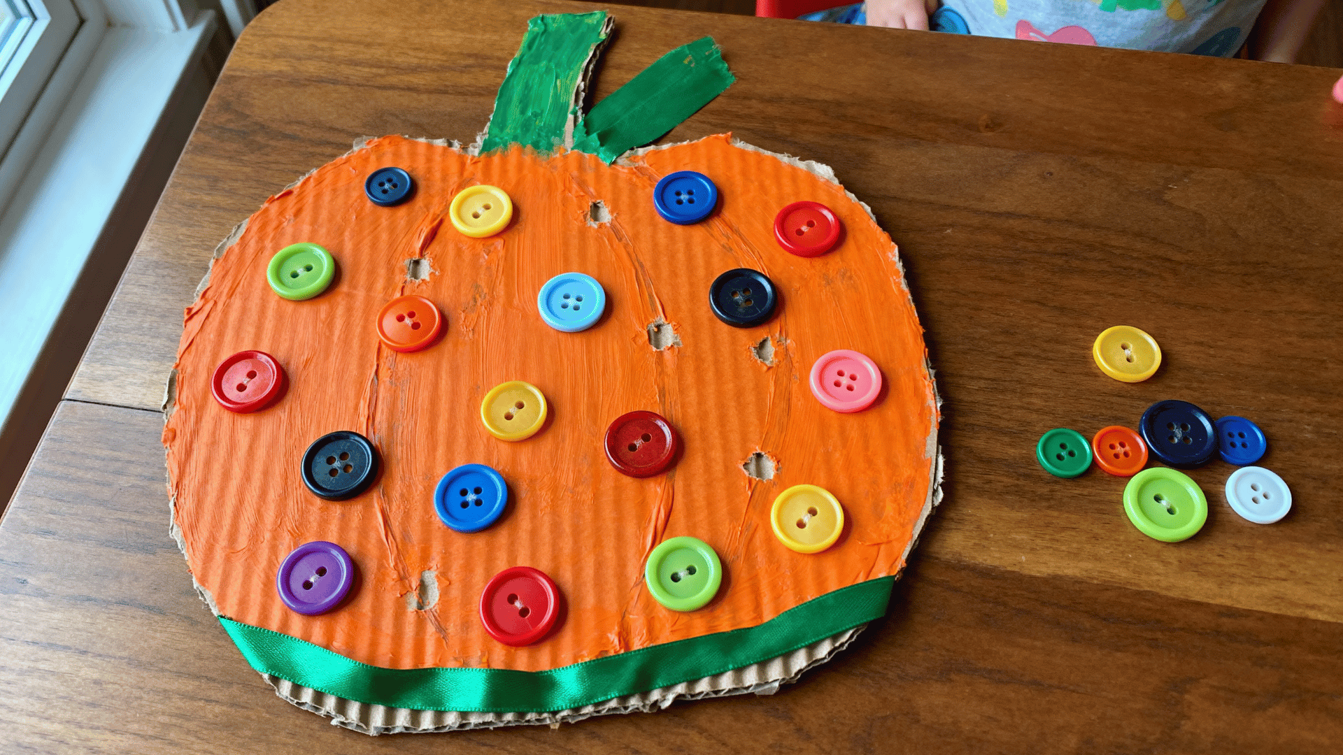 button-decorated pumpkin craft covered with colorful buttons and green trim