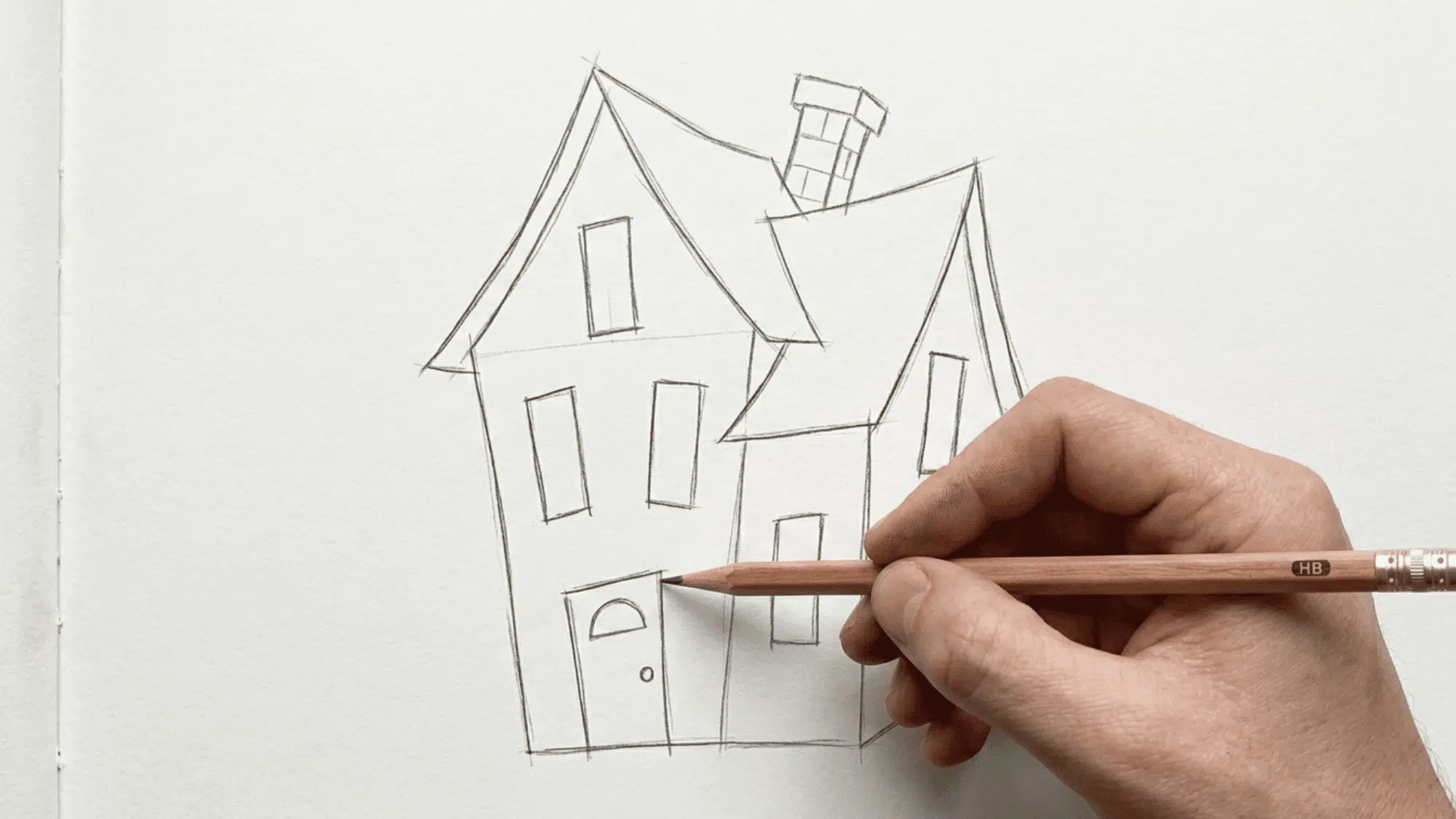 hand drawing an easy haunted house sketch with crooked roof and spooky windows on paper.