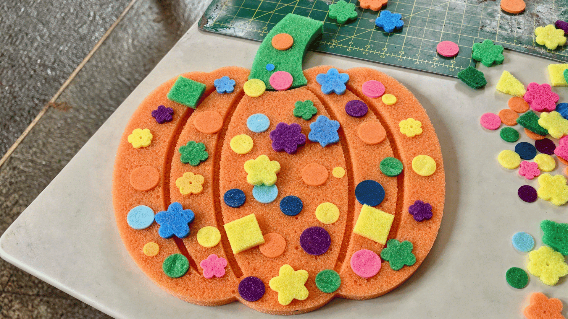 foam pumpkin decorated with colorful stickers, sequins, and rhinestones by a toddler