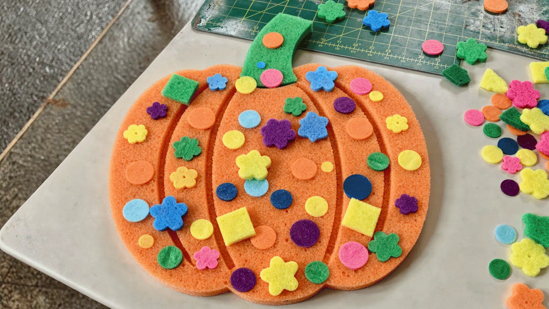 foam pumpkin decorated with colorful stickers, sequins, and rhinestones by a toddler