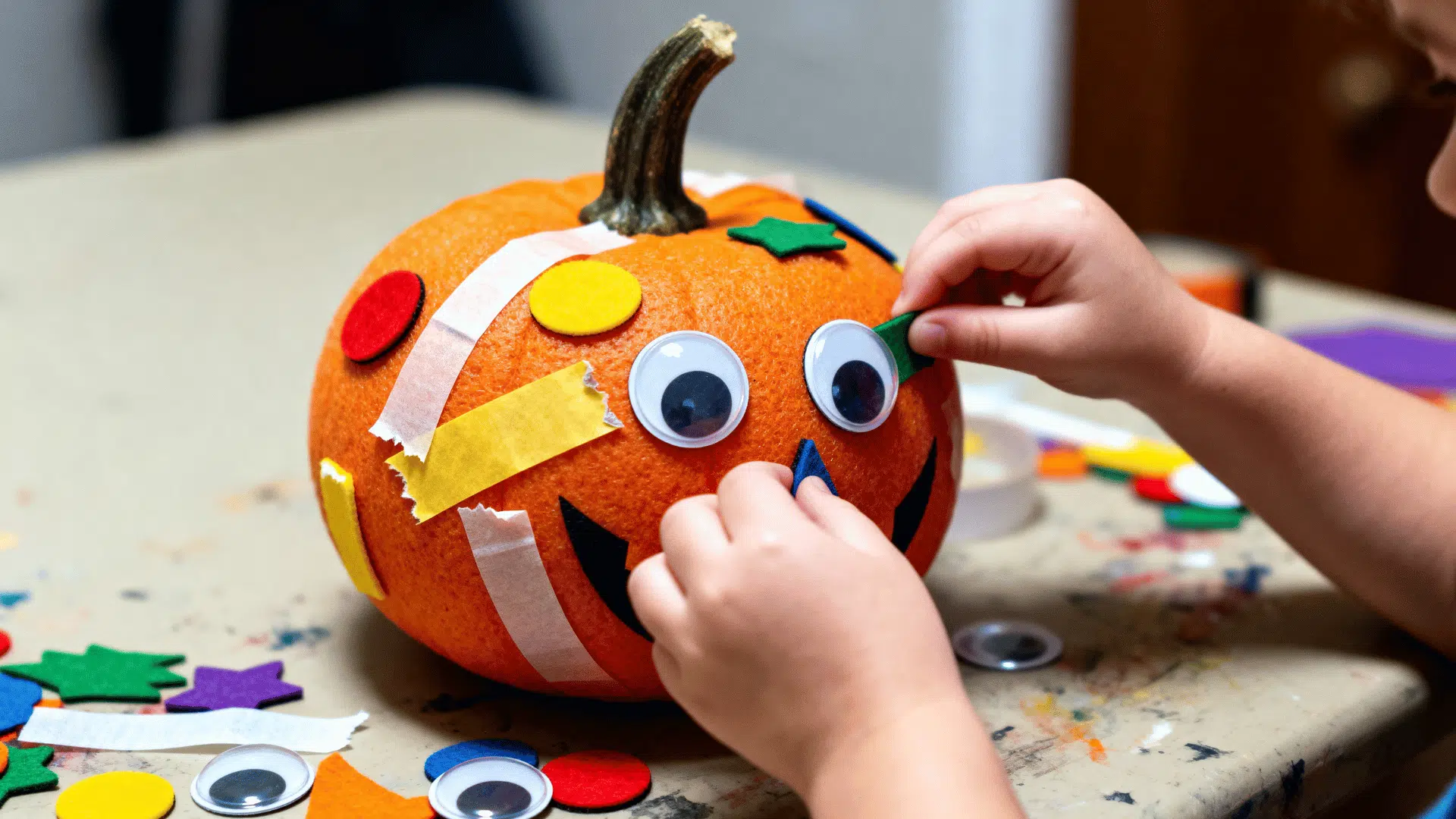 toddler-decorated no-carve pumpkin covered with colorful stickers and washi tape.