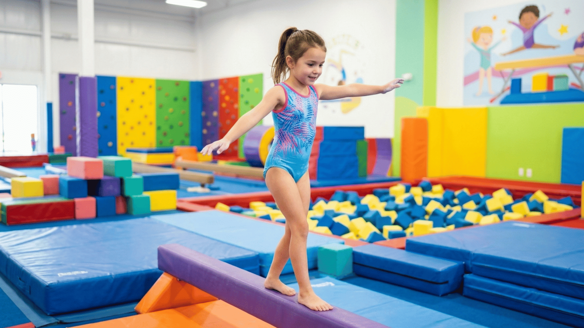 young gymnast balances carefully on a beam in a colorful indoor gymnastics facility.