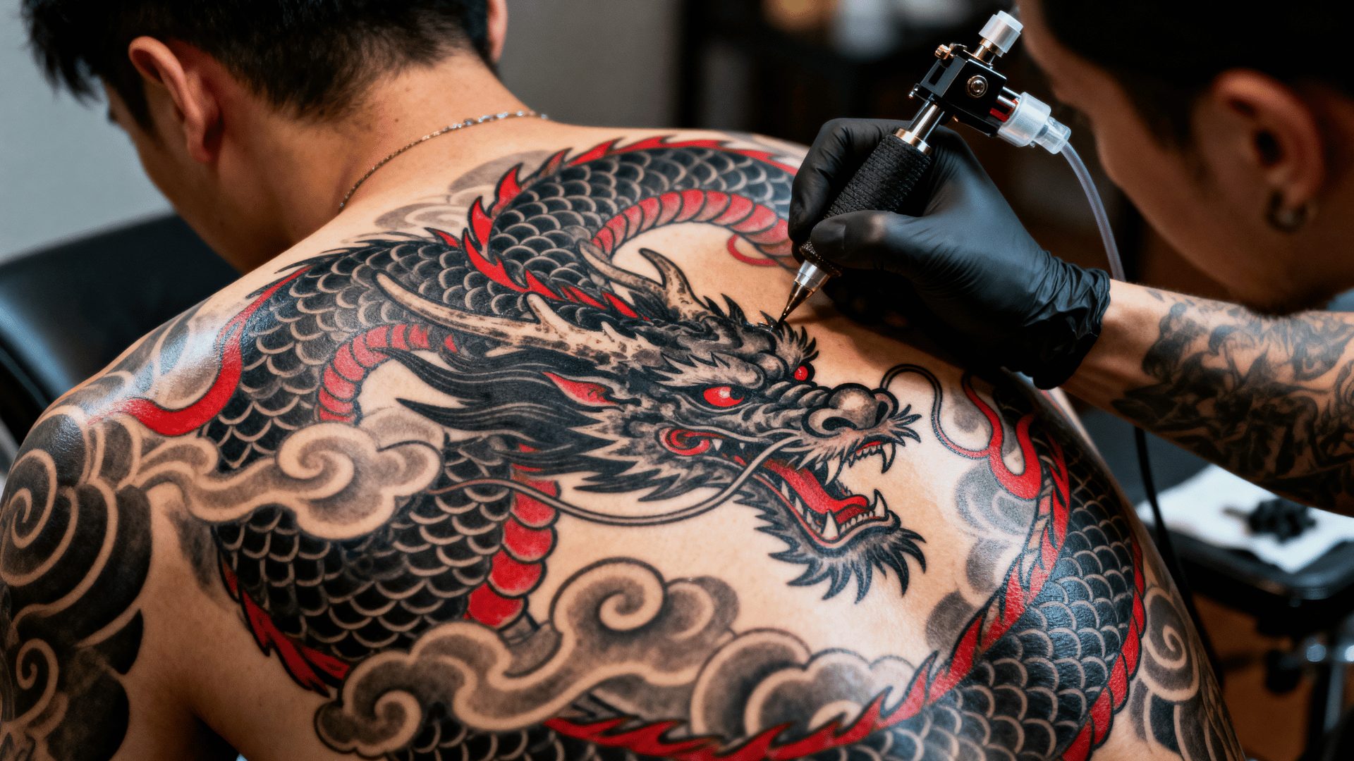 large Japanese dragon tattoo being created across a person's upper back, featuring detailed scales, clouds, and traditional artwork