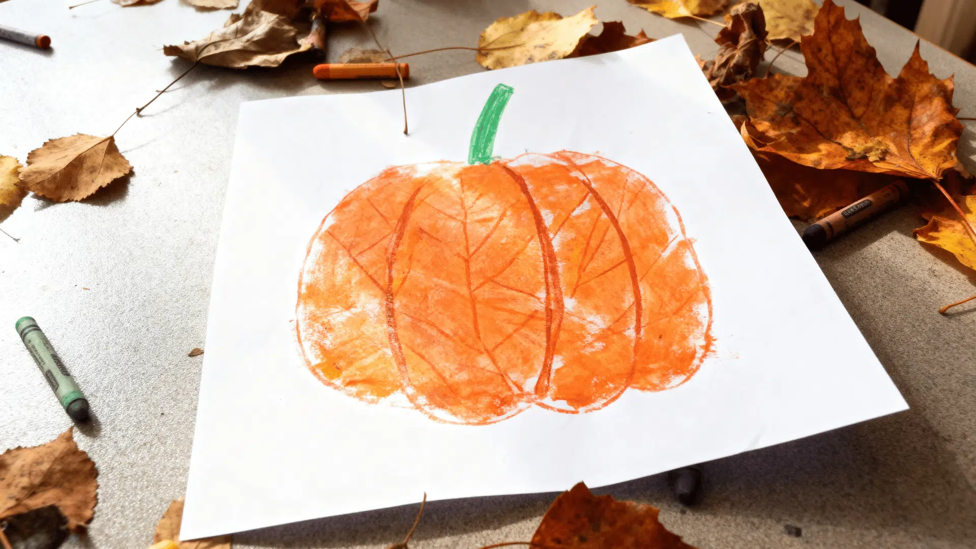 pumpkin leaf rubbing art made with orange crayons and real leaves.