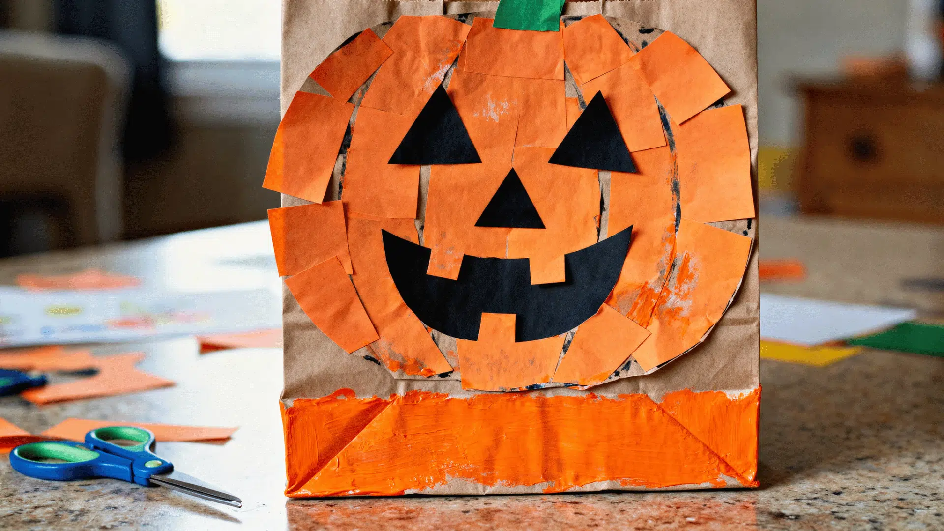 paper bag pumpkin puppet decorated with orange paper and a jack-o'-lantern face