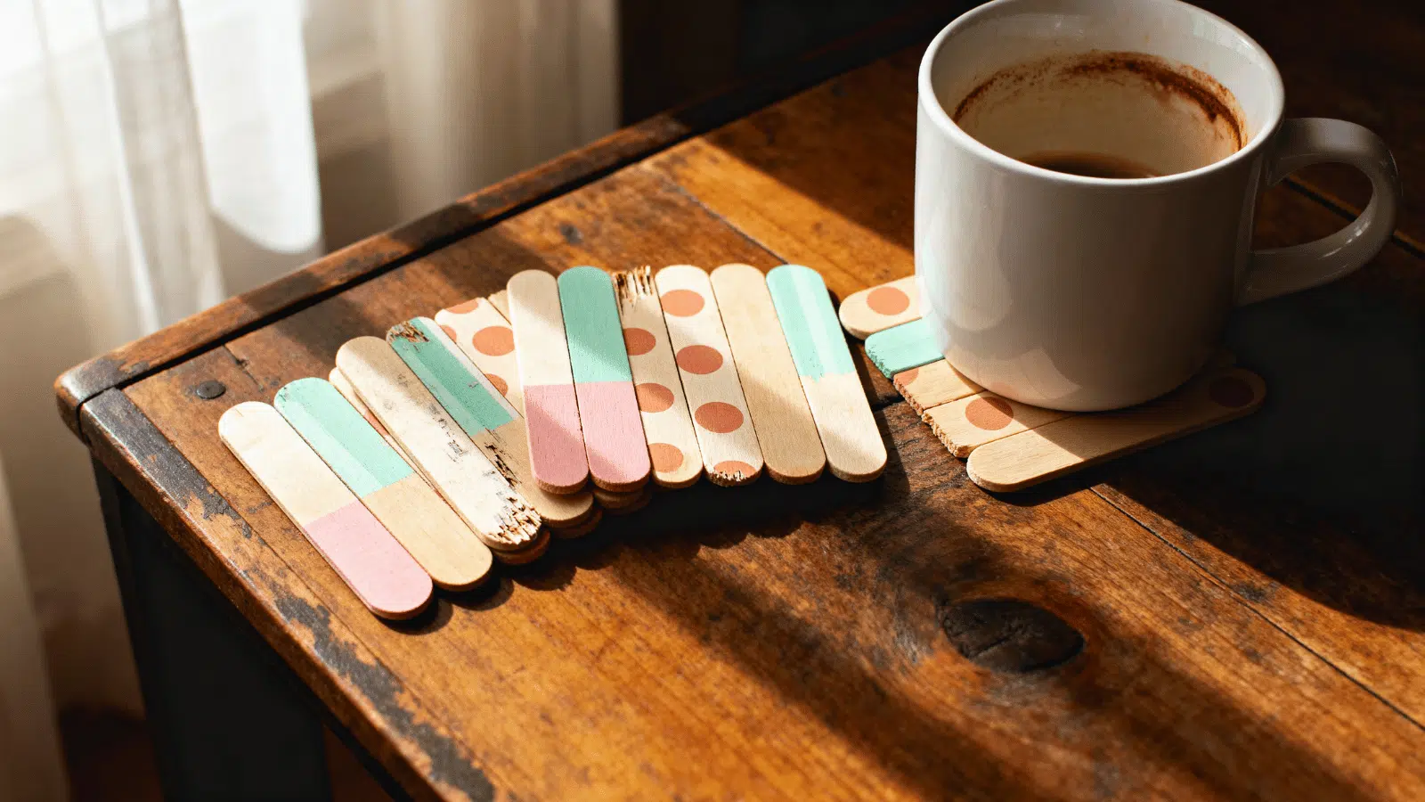 handmade popsicle stick coasters with painted patterns arranged on a coffee table at home.