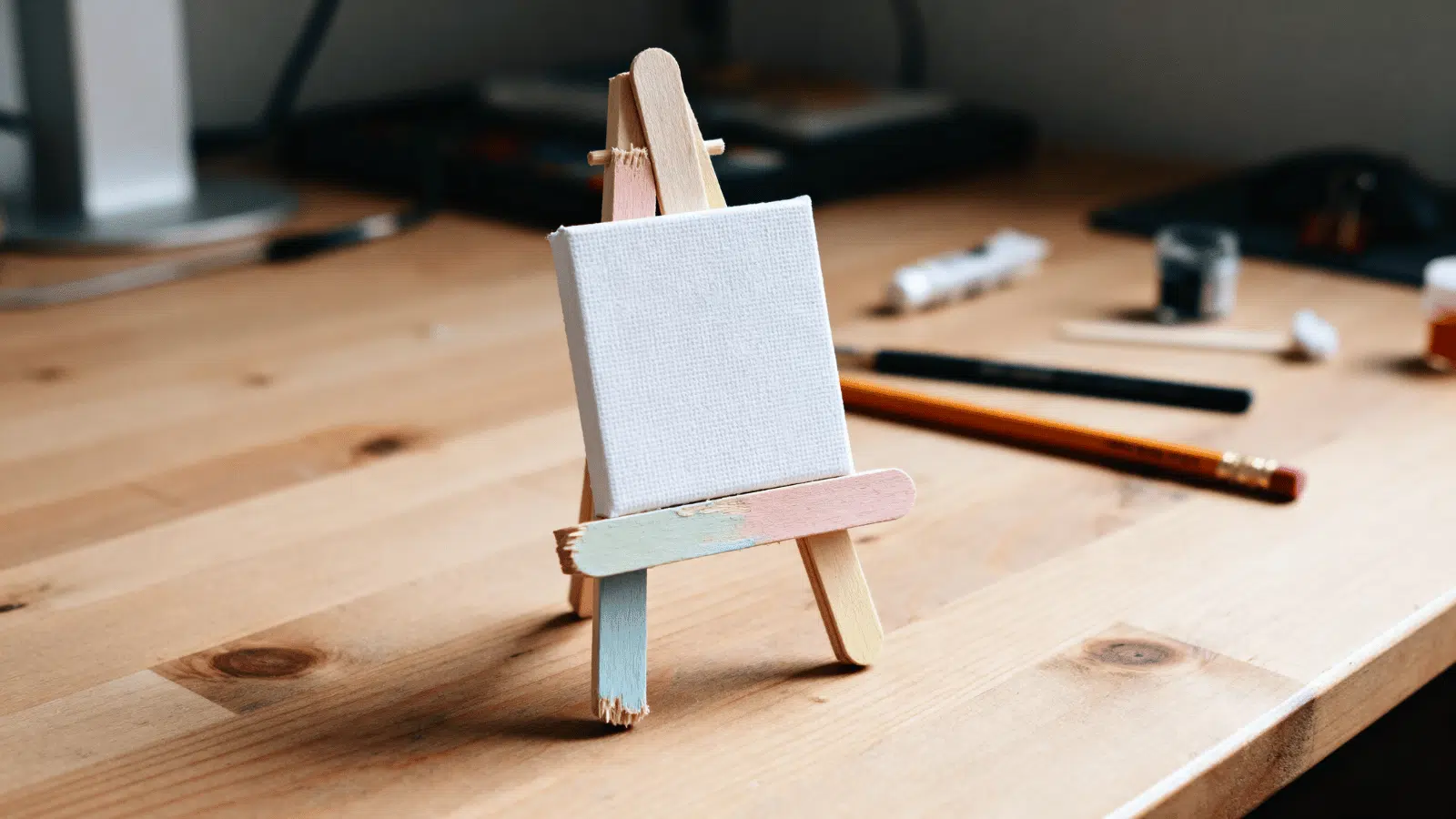 handmade popsicle stick mini easel holding a small card on a desk in soft natural light.