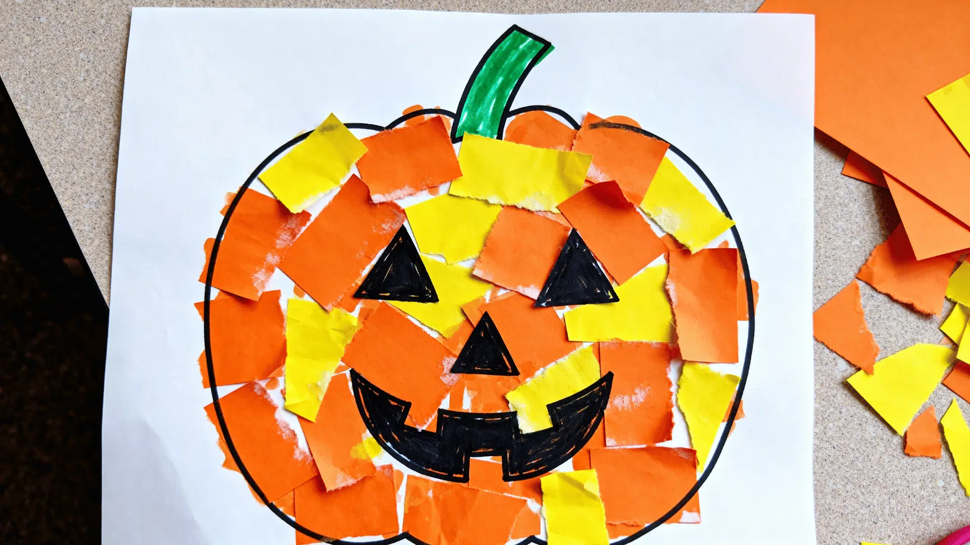 torn paper mosaic pumpkin craft made with orange and yellow paper pieces