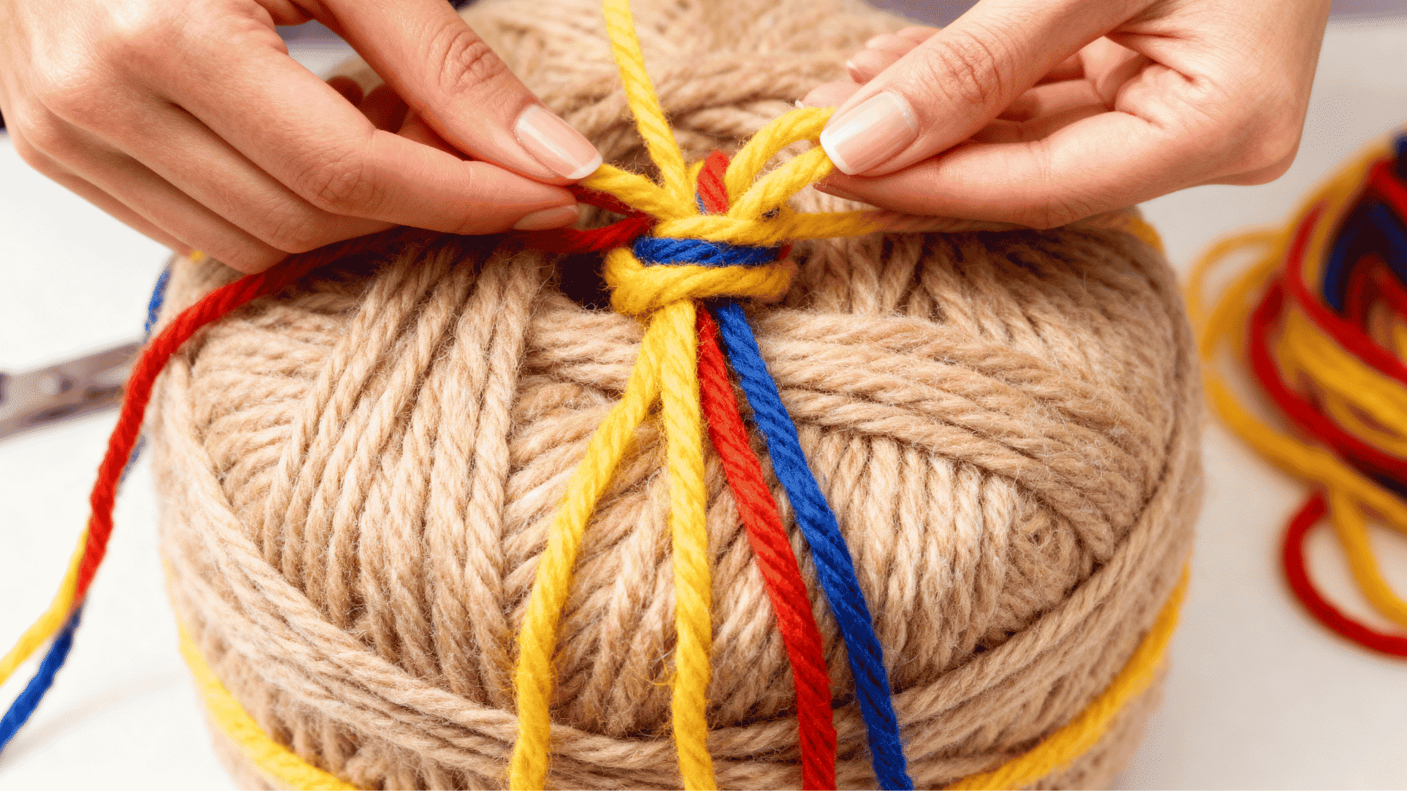 Wrapped yarn bundle being tied tightly in the center to hold the pom pom together