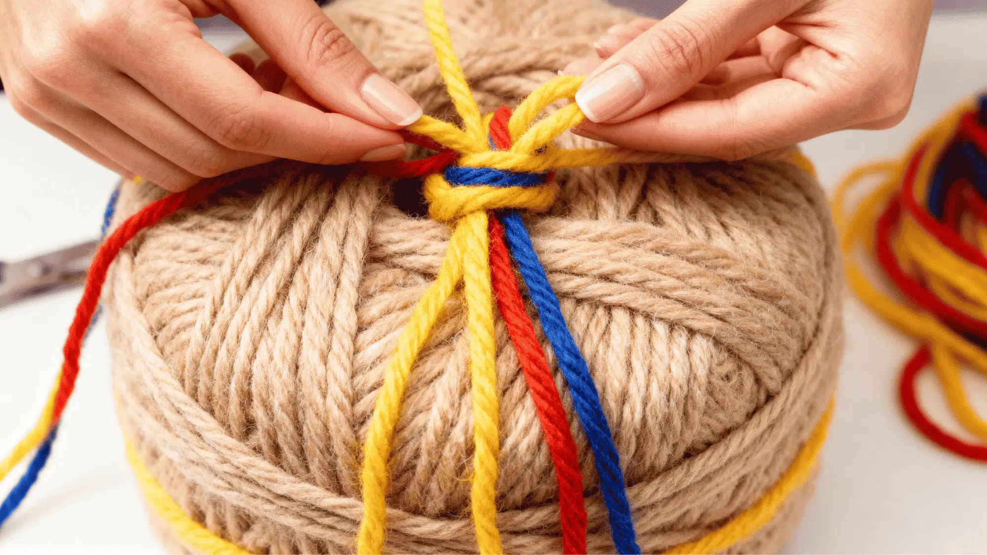 Wrapped yarn bundle being tied tightly in the center to hold the pom pom together