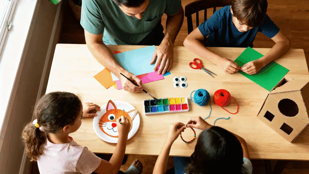 aA parent and two kids doing fun arts and crafts together at home, simple and affordable craft ideas for kids ages 6 to 12