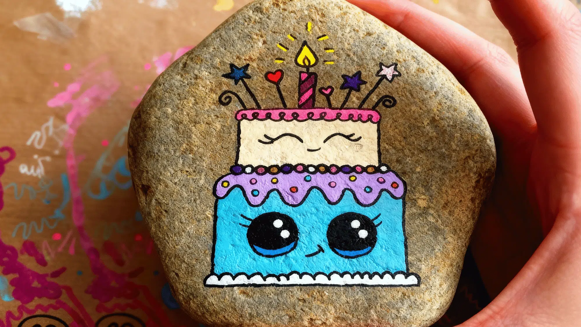 Painted rock with a cute birthday cake and candle