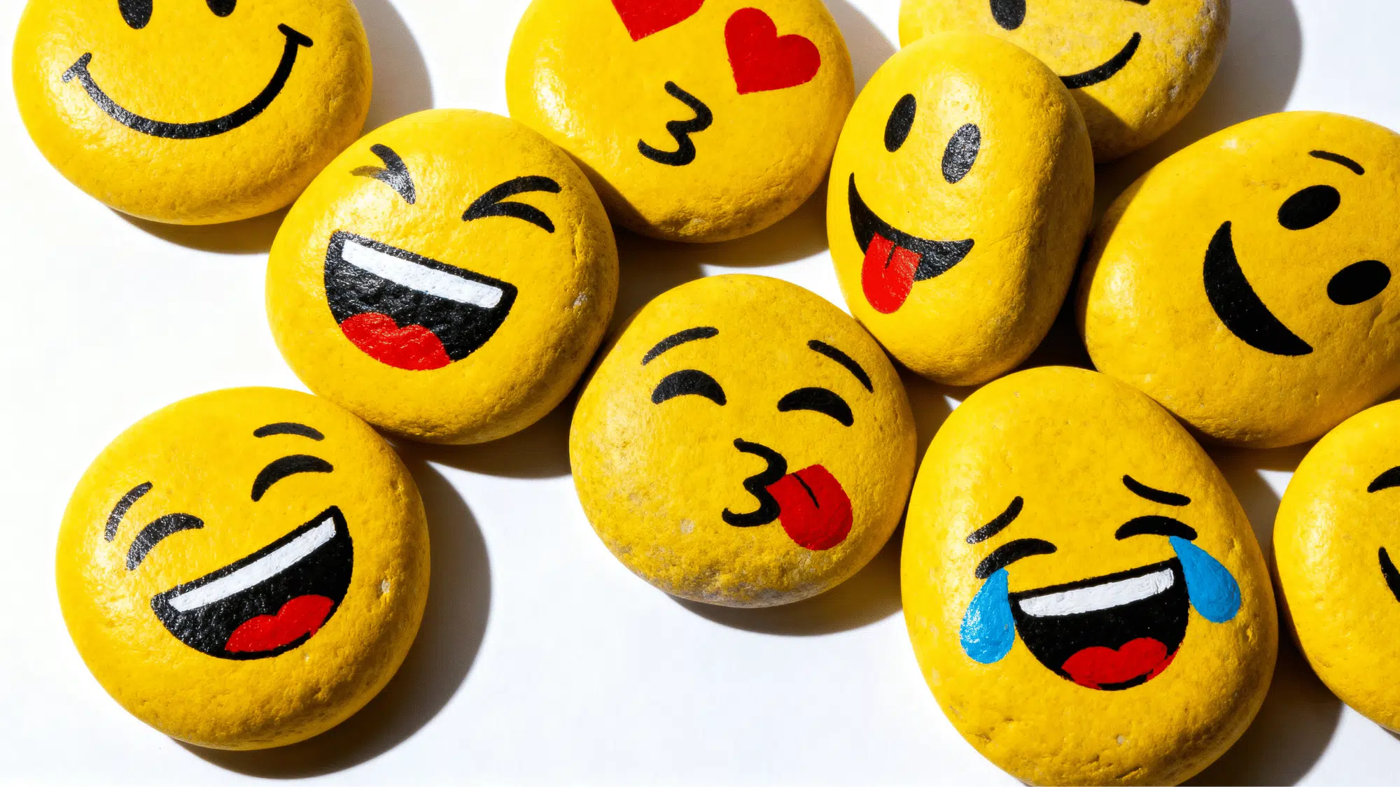 Yellow rocks painted with happy emoji faces