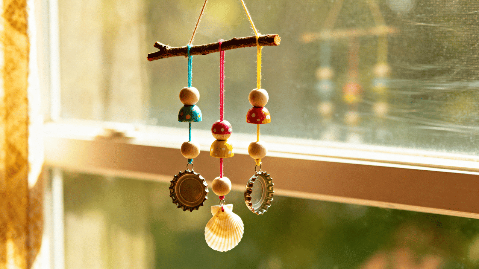 a handmade diy wind chime made with beads and shells by kids at home, a creative and simple craft for ages 6 to 12