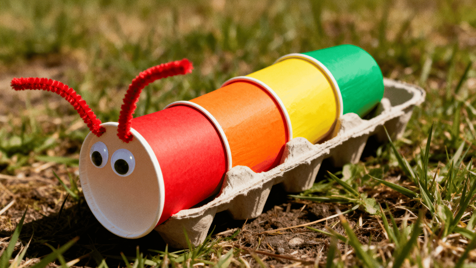 a rainbow colored egg carton caterpillar craft with googly eyes made by kids, a fun simple craft for ages 6 to 12