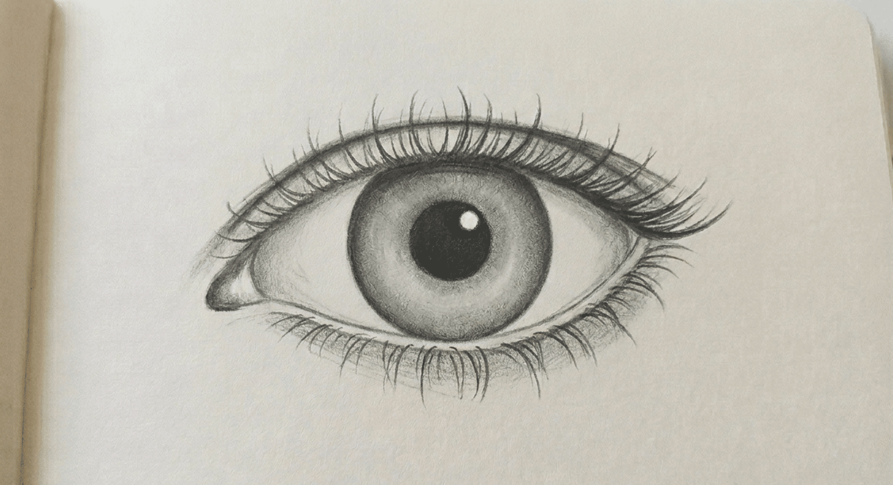 completed pencil drawing of a realistic human eye with detailed shading, iris texture, and defined eyelashes.