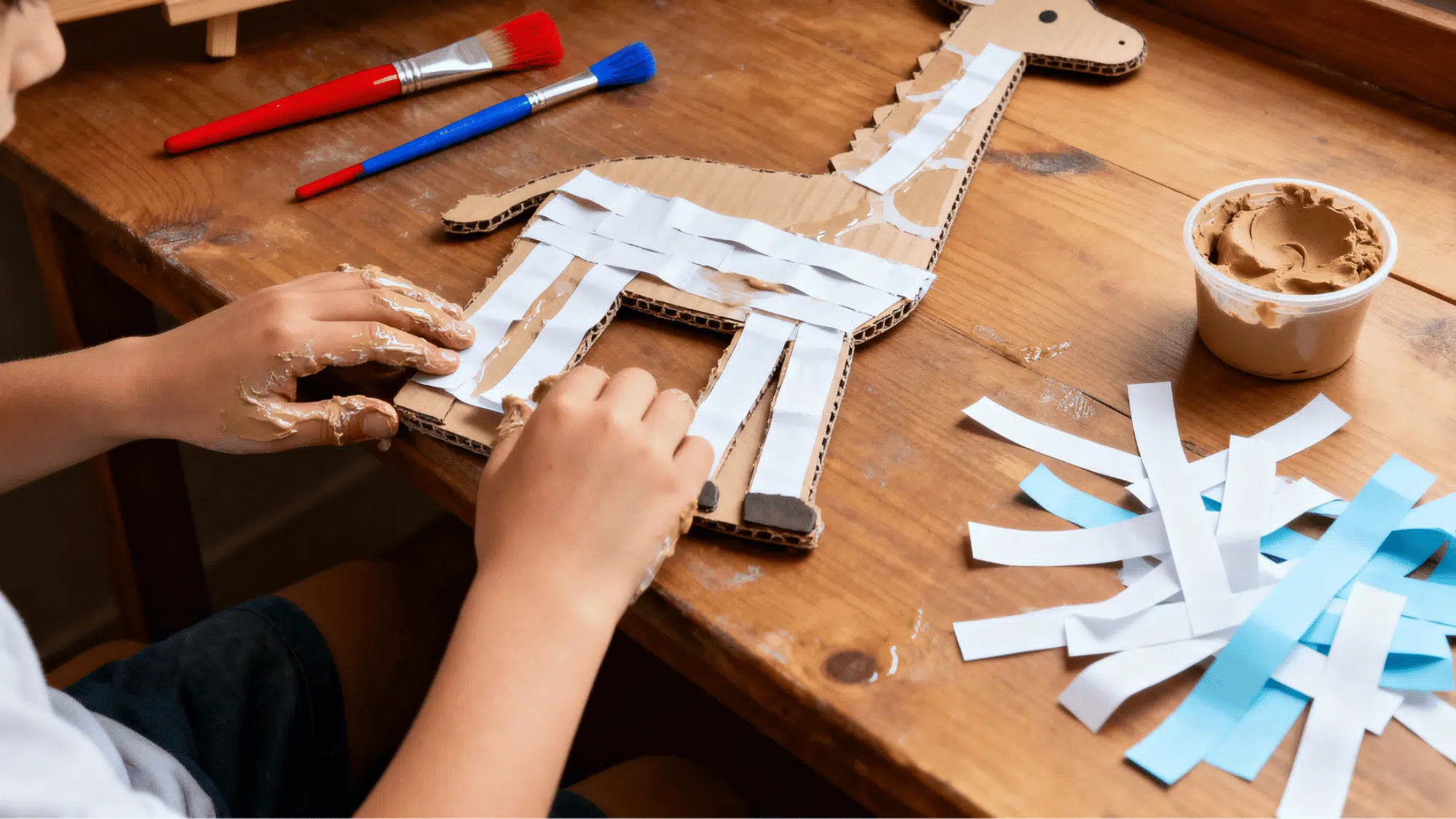 Child making paper-mache animal models with paint and clay