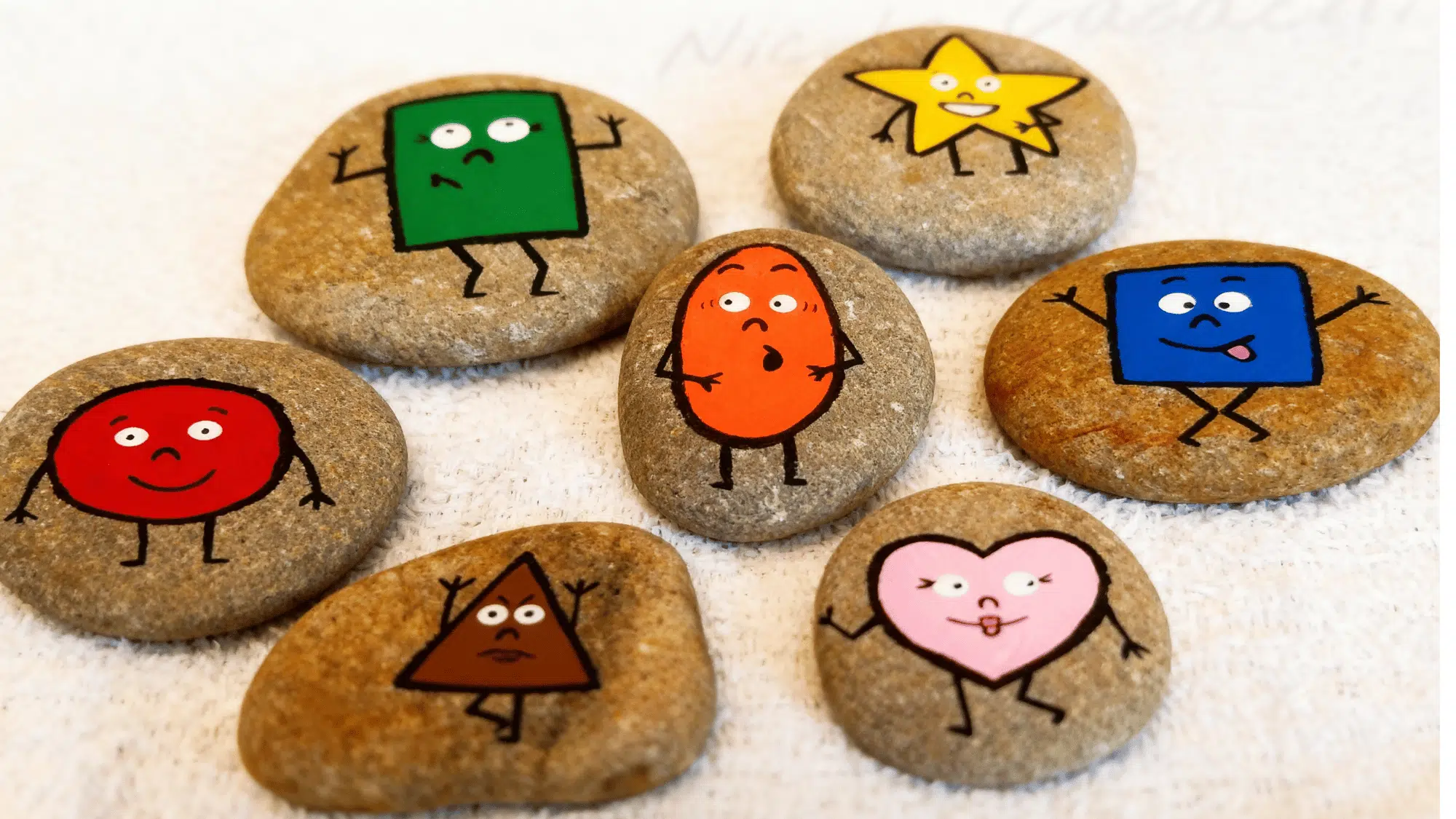 Playful rocks painted as colorful shapes with smiling faces and stick limbs.