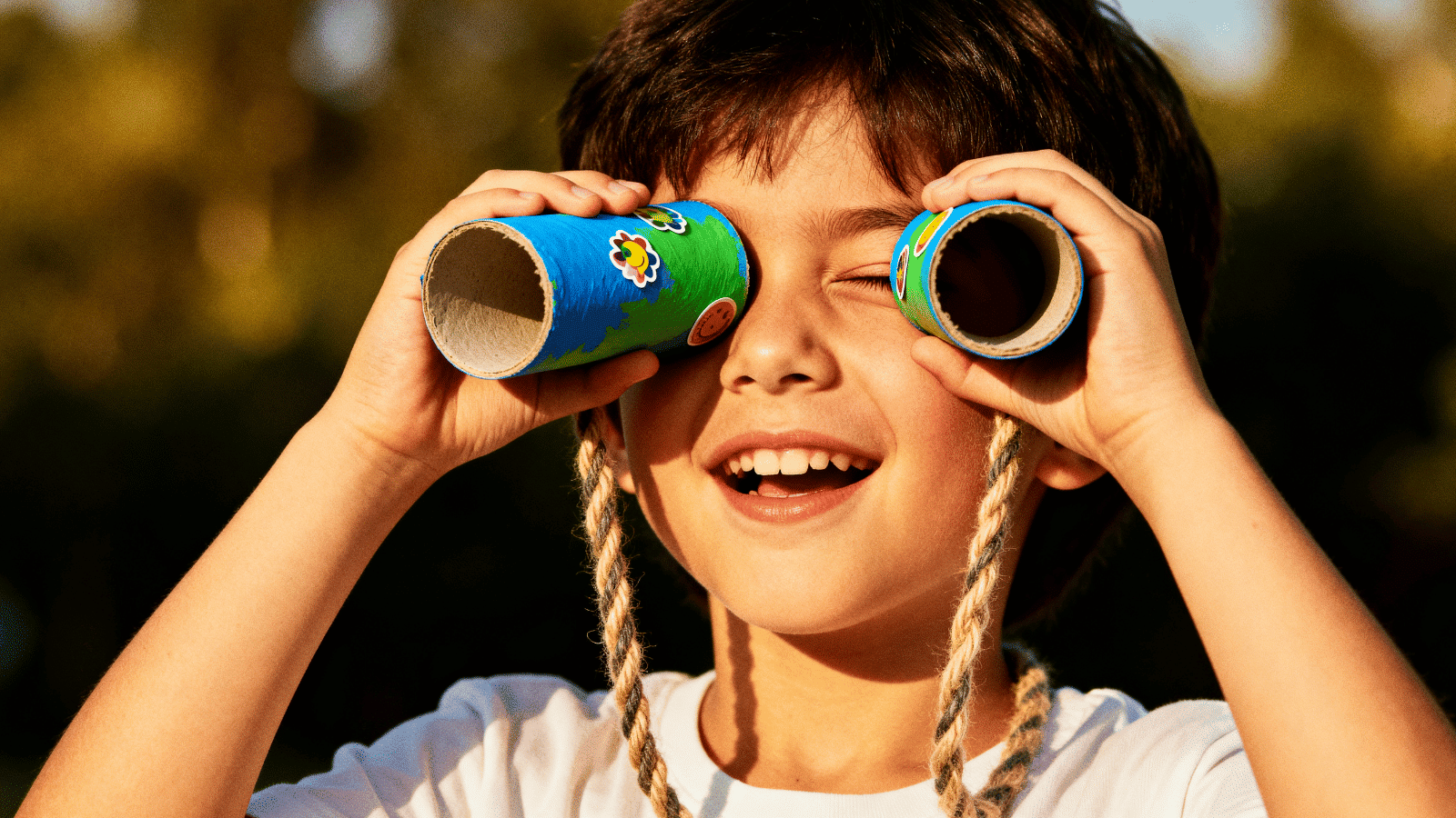 a child using DIY toilet roll binoculars decorated with paint and stickers, a fun simple craft for kids at home