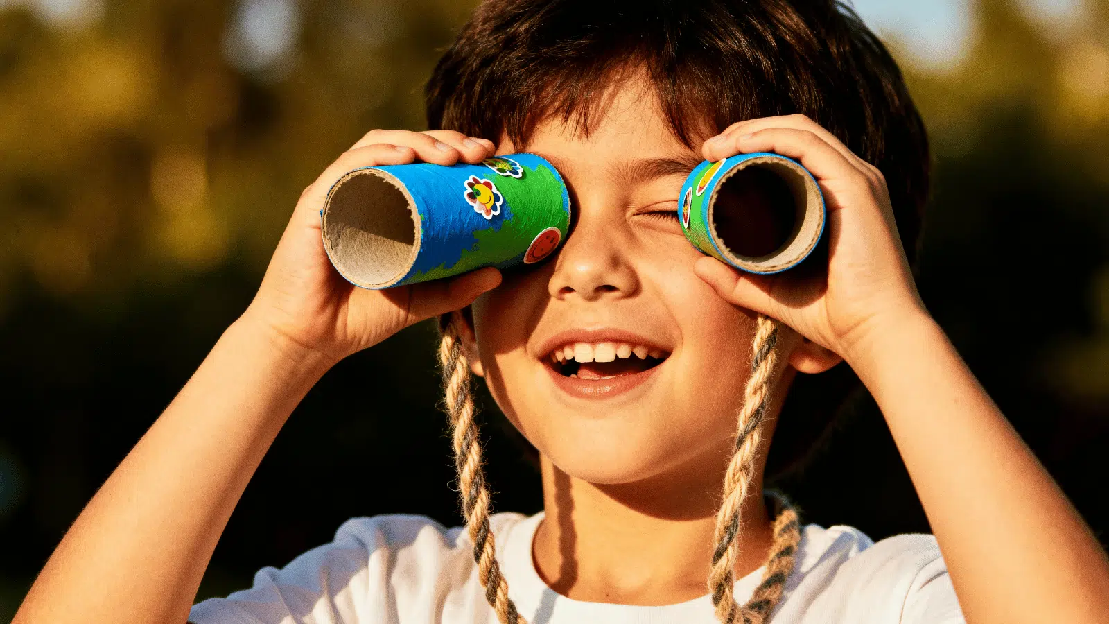 a child using DIY toilet roll binoculars decorated with paint and stickers, a fun simple craft for kids at home