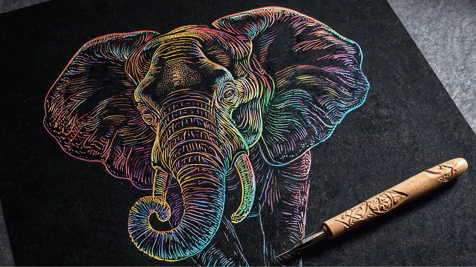 scratch art elephant drawing with vibrant rainbow lines revealed against a black background