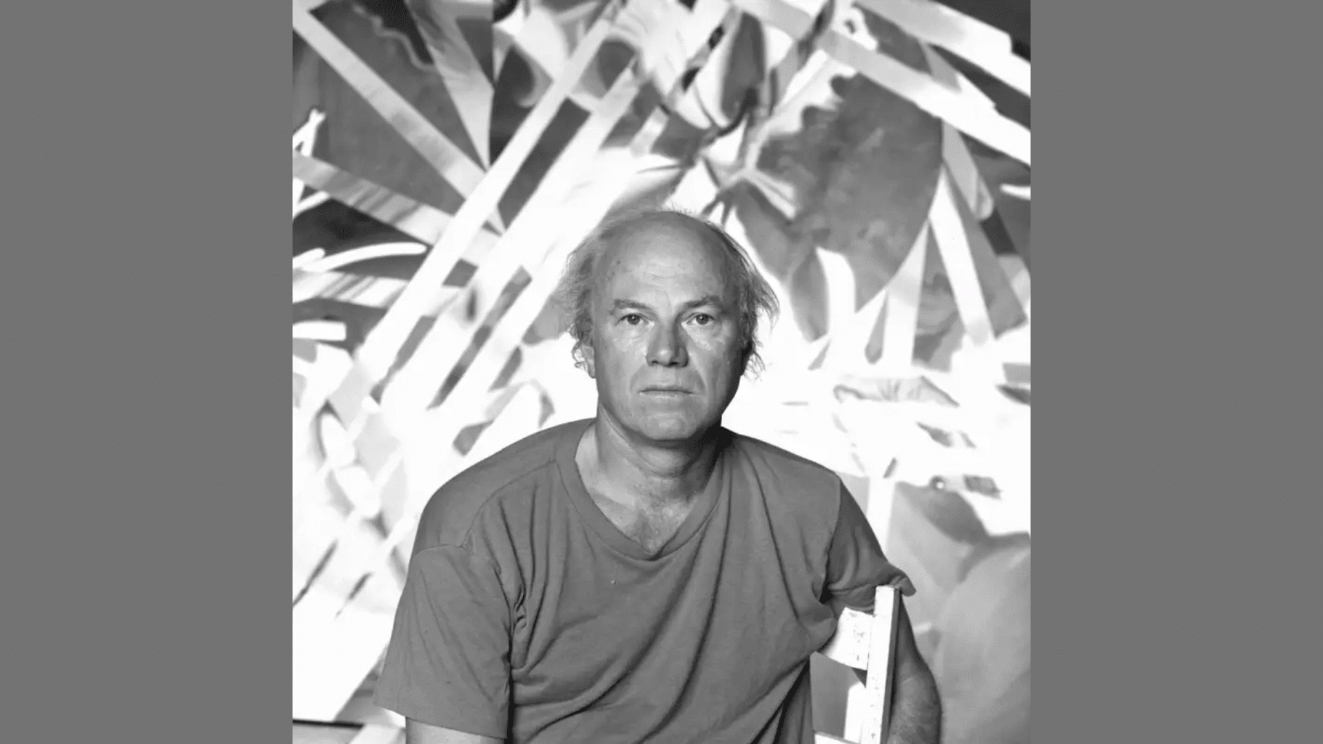 black and white portrait of artist James Rosenquist in a T-shirt with an abstract painting background
