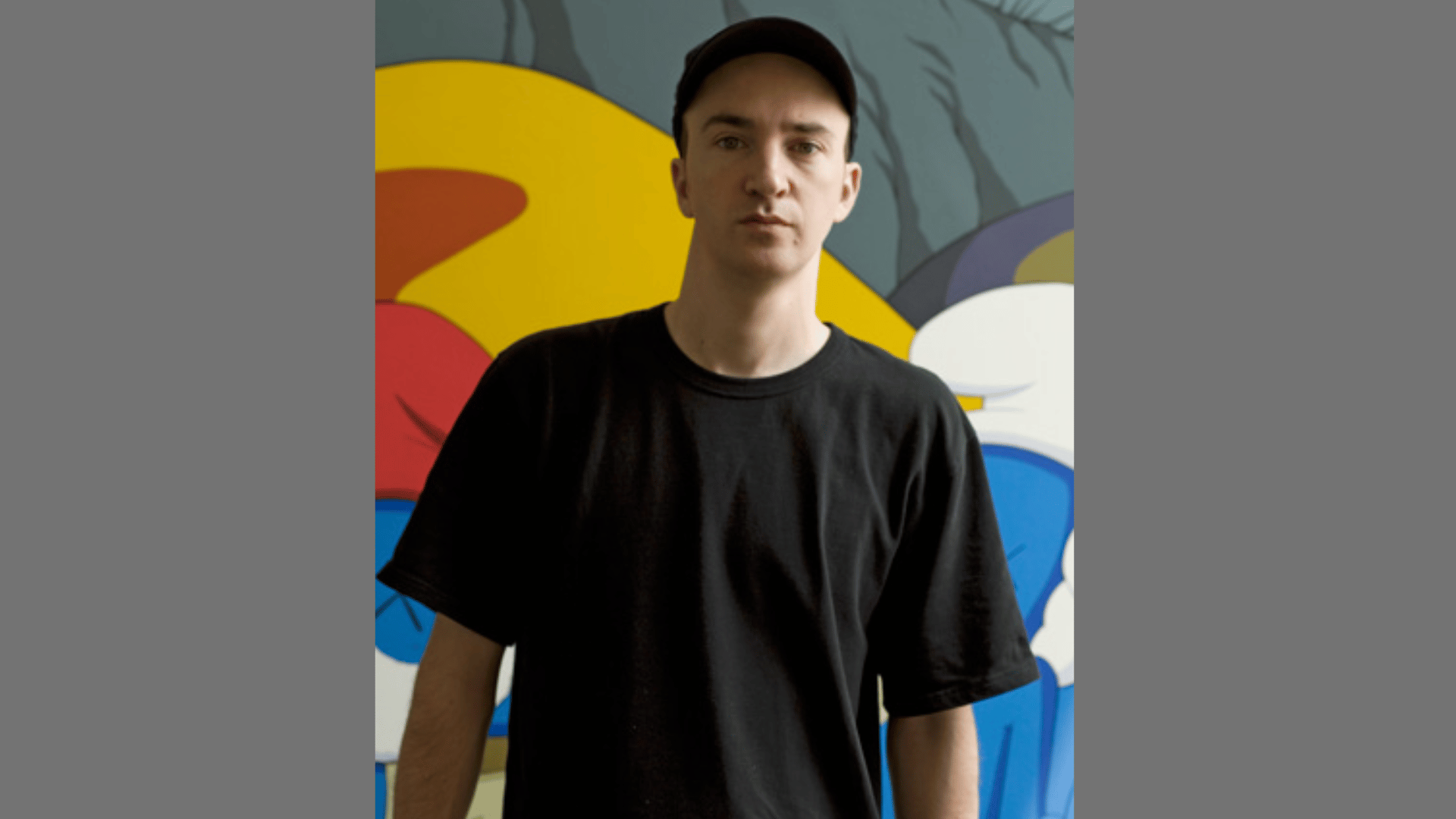 a portrait of the artist KAWS wearing a black T-shirt and cap against a colorful graphic background