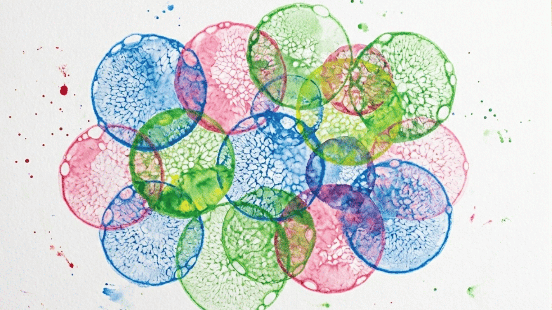 overlapping bubble print circles in blue pink and green on white paper