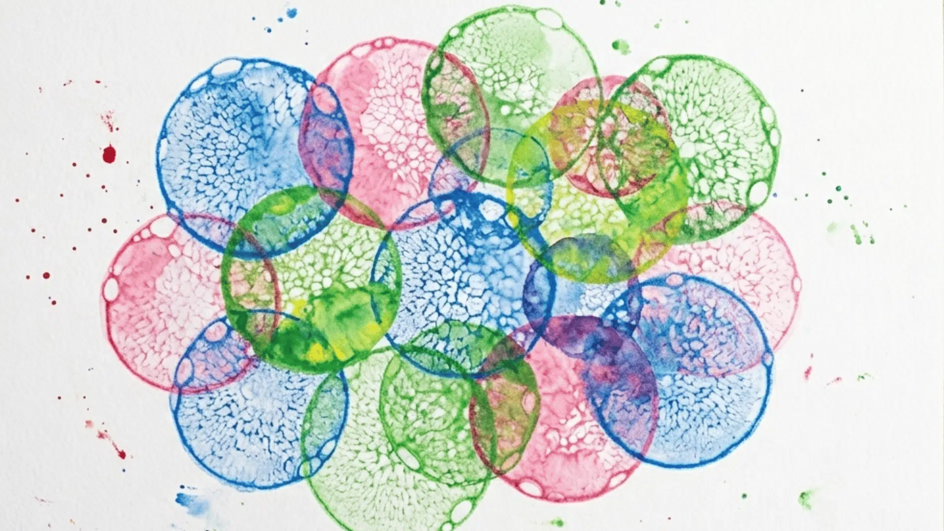 overlapping bubble print circles in blue pink and green on white paper