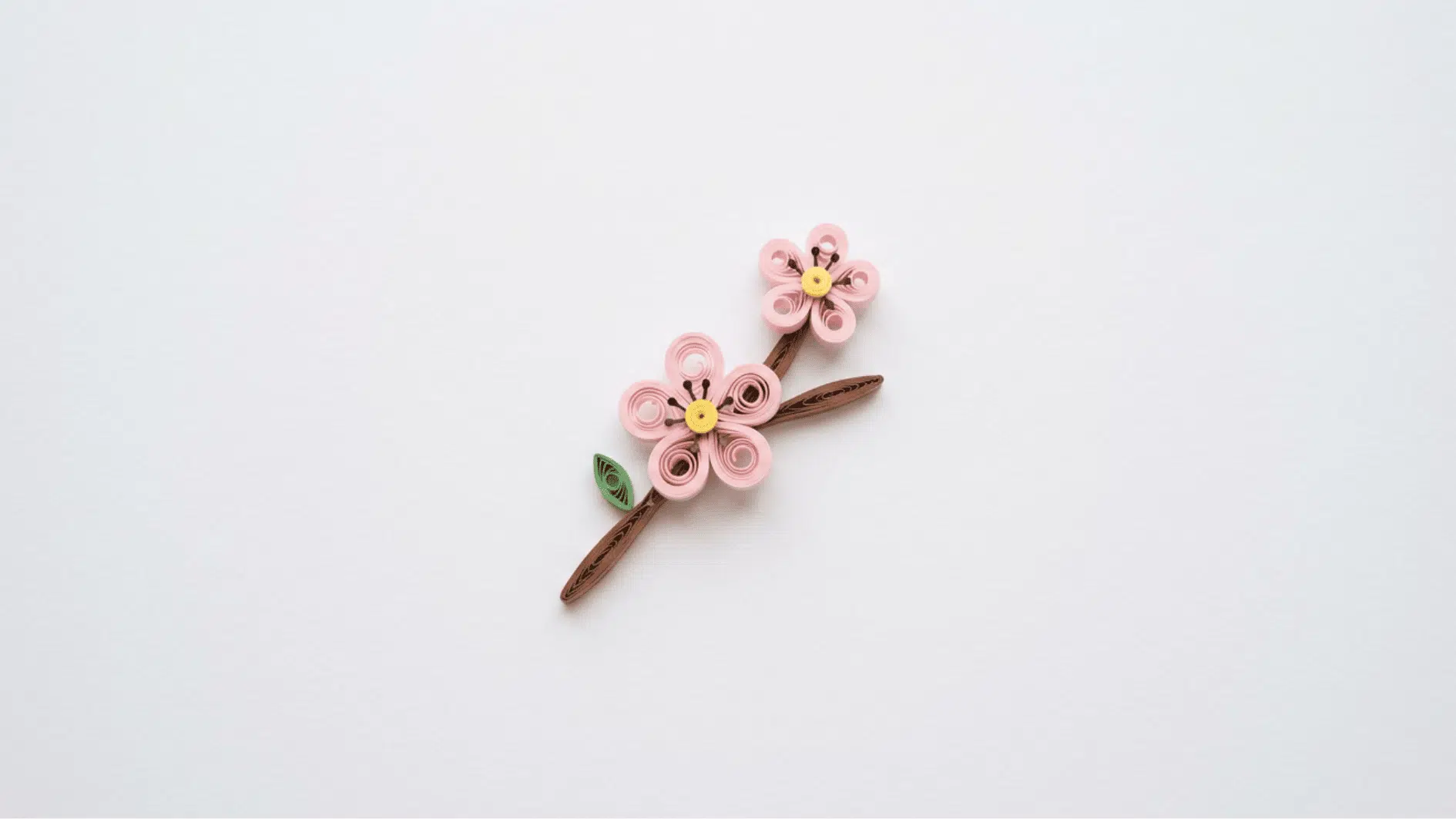 quilled paper cherry blossom branch with pink flowers yellow centers on white background