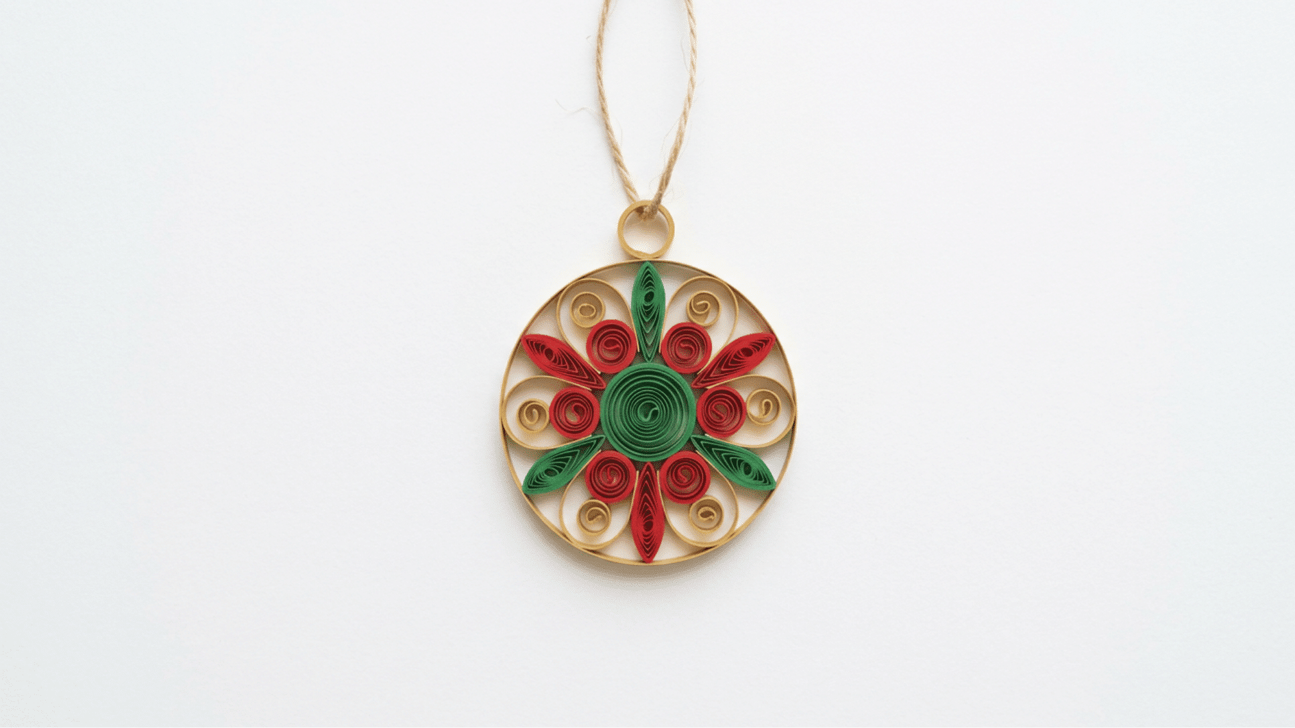 round quilled paper christmas ornament in gold red and green hanging from twine on white background
