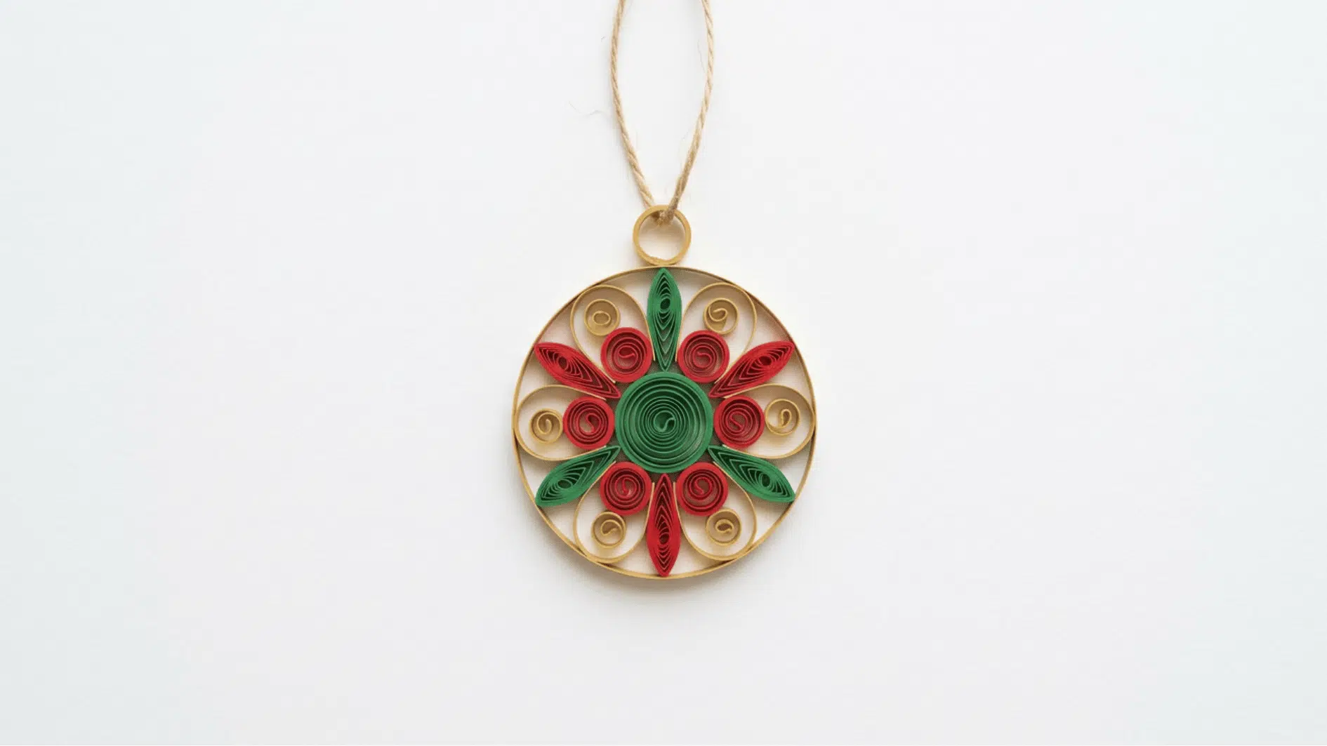 round quilled paper christmas ornament in gold red and green hanging from twine on white background