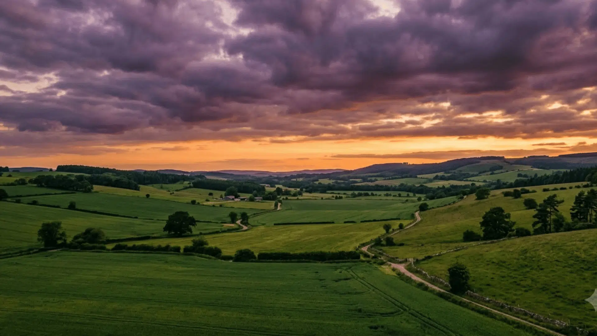 cinematic landscape still color graded toward a triadic scheme of green fields, orange sky, and violet clouds